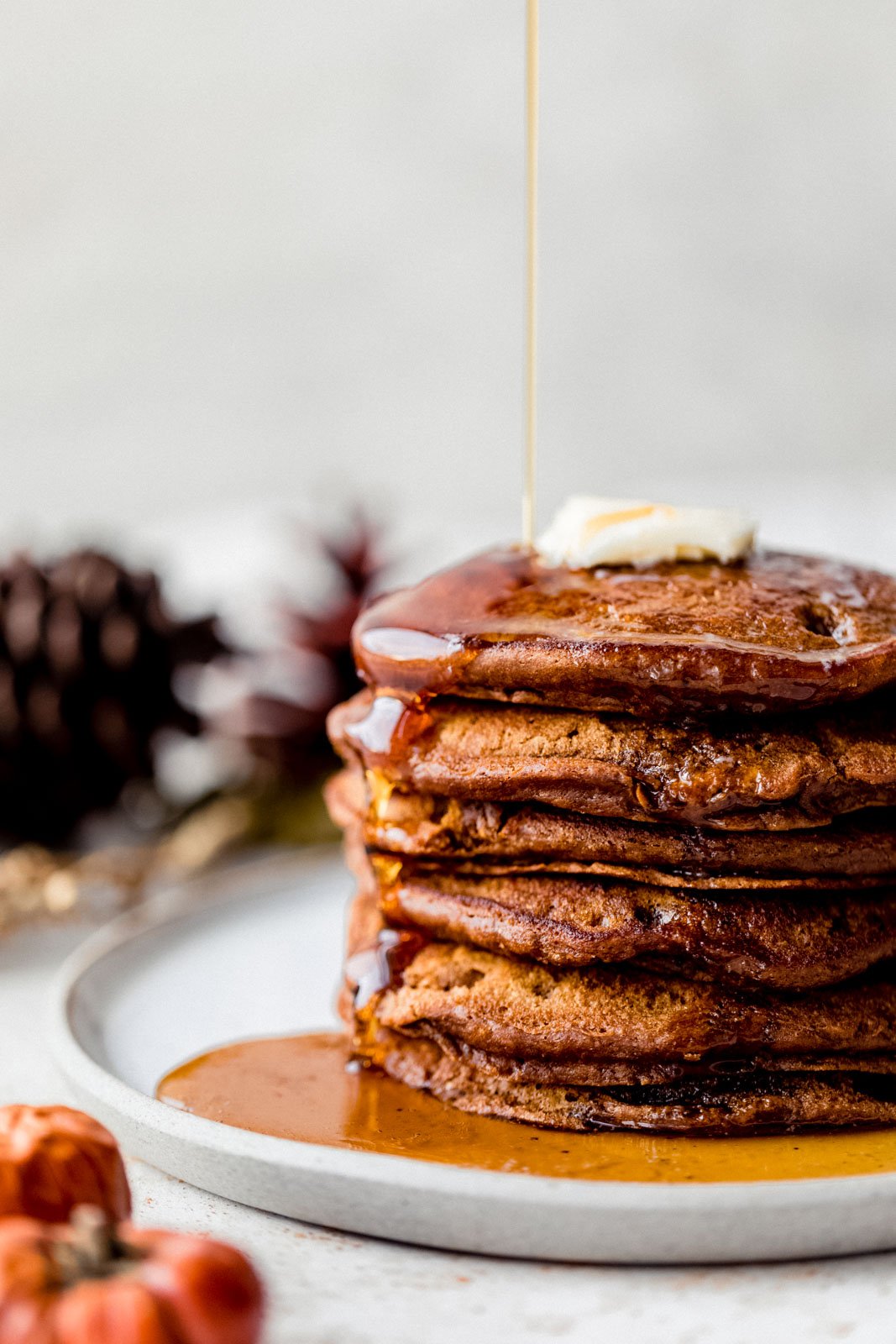 Tortitas de pan de jengibre increíblemente esponjosas hechas con harina de trigo integral, especias calientes y melaza dulce perfecta. Estos panqueques de pan de jengibre más saludables no contienen productos lácteos y están perfectamente condimentados, ¡oh, tan esponjosos, el brunch navideño perfecto! Panqueques de pan de jengibre saludables apilados en el plato