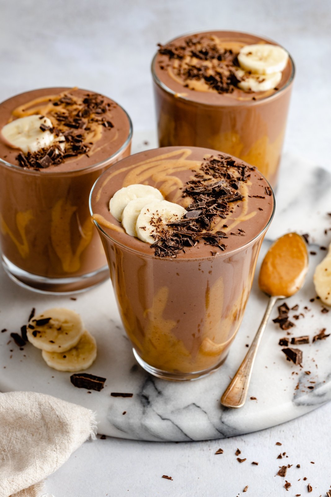 ¡Delicioso batido cremoso de chocolate con mantequilla de maní y plátano que sabe como el batido de Wendy's! Esta receta saludable de licuado de plátano y chocolate está hecha con solo cinco ingredientes y es fácil de personalizar con su potenciador nutricional favorito. ¡Perfecto para el desayuno, la merienda o incluso el postre! Batido de plátano con mantequilla de maní y chocolate de tres tazas