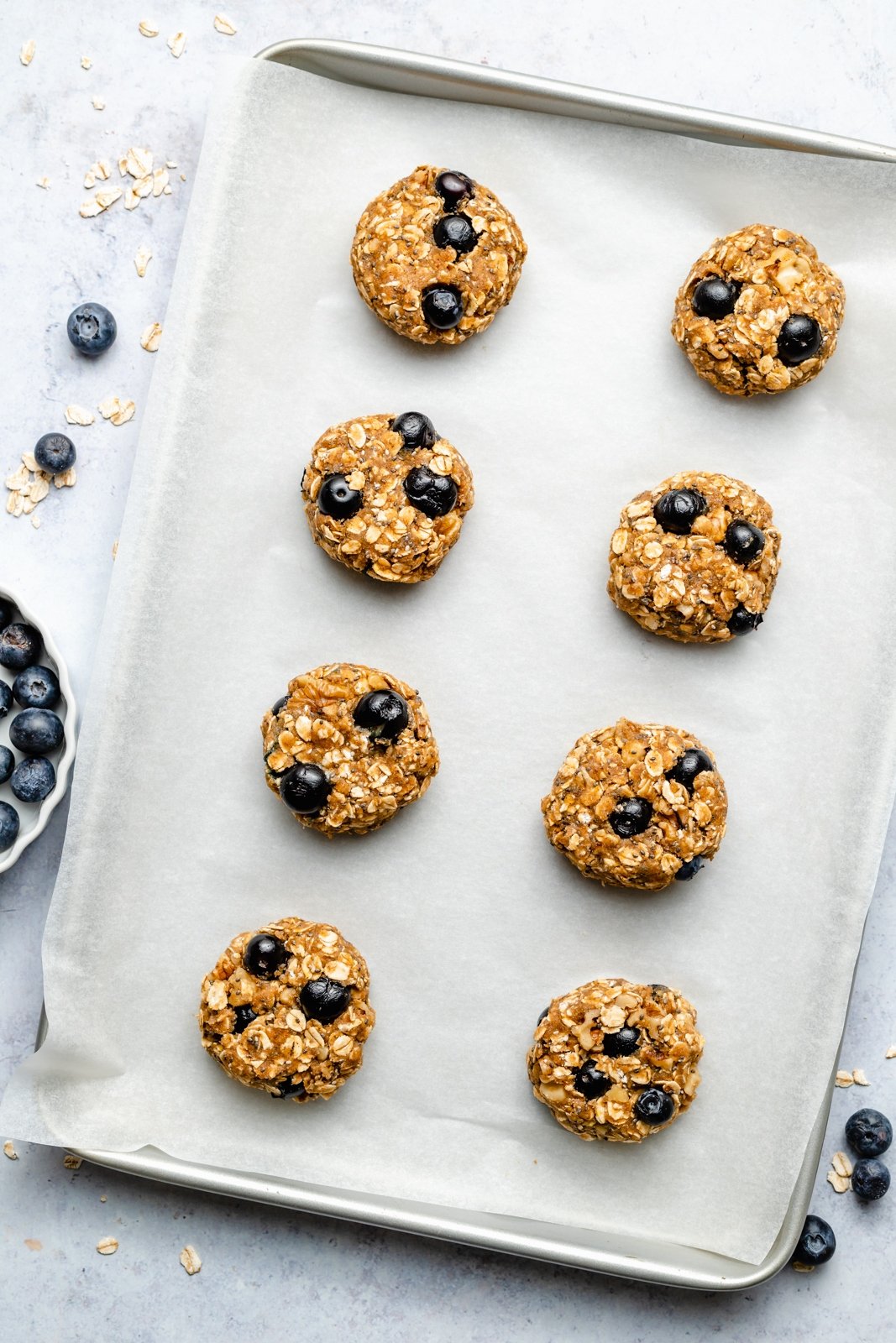 ¡Un plato de galletas de desayuno de arándanos veganas y sin gluten que saben igual que muffins de arándanos! Estas saludables galletas de desayuno de arándanos son naturalmente dulces y están llenas de nutrientes de semillas de chía, lino, avena, nueces y más ingredientes. Perfectas para congelar, ¡Es el desayuno o merienda perfecto para las semanas ocupadas! Galletas de desayuno de arándanos sin hornear en una bandeja para hornear
