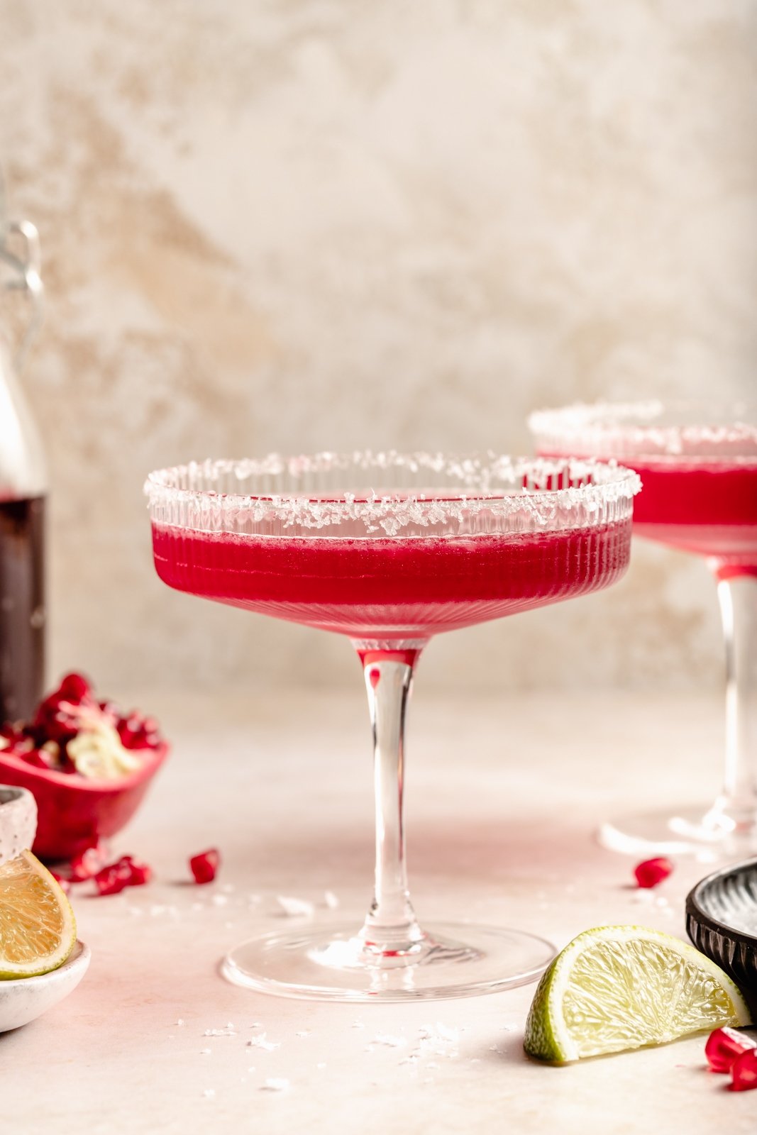 Una margarita de granada deliciosa y fácil hecha con cuatro ingredientes simples, ¡el cóctel refrescante perfecto! Use jugo de granada comprado en la tienda o hecho en casa y jarabe simple para crear un maravilloso cóctel perfecto para el entretenimiento. Margaritas caseras de granada en un vaso con borde de sal