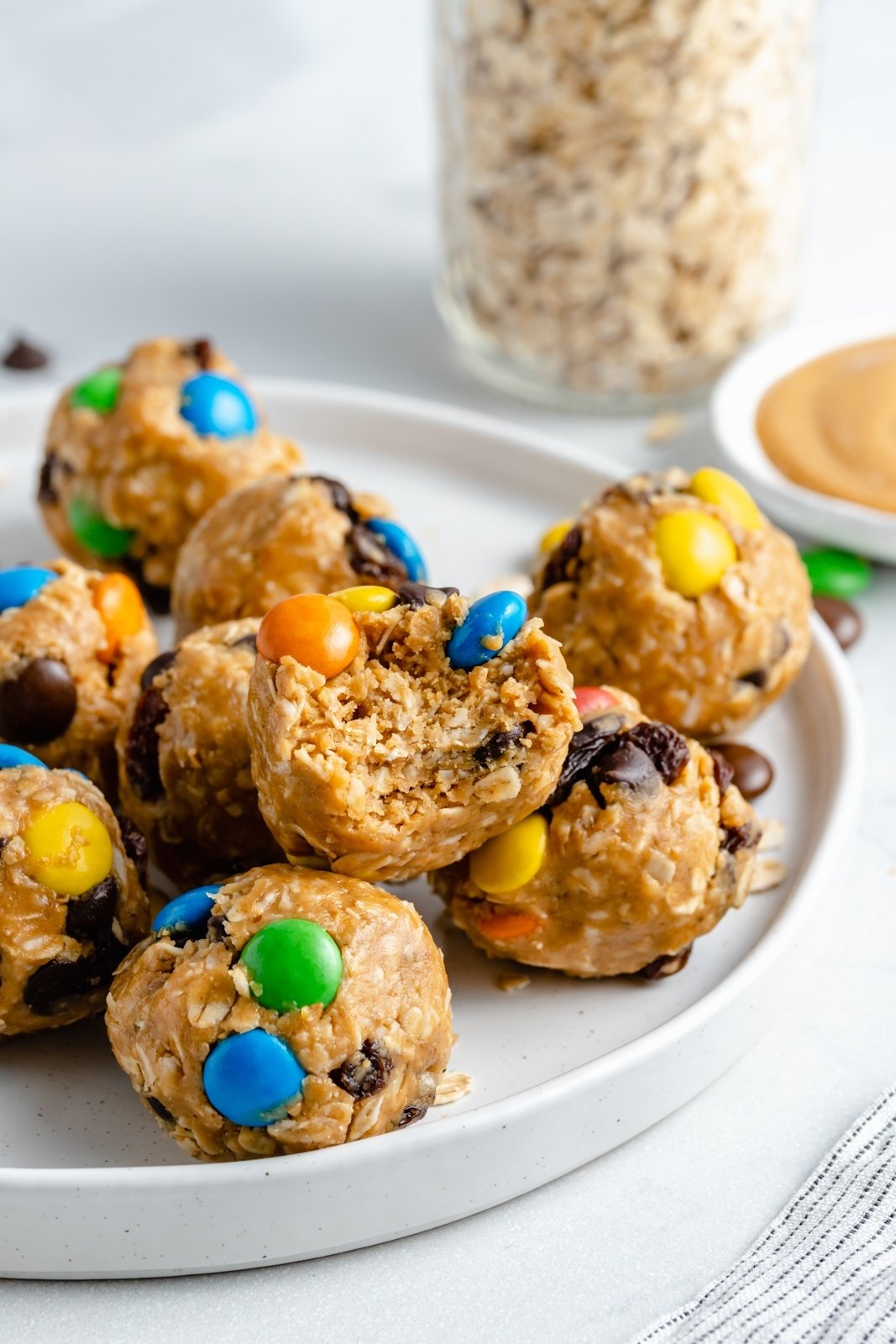 Bocadillos saludables ricos en proteínas, ¡perfectos para viajar o simplemente para llevar! Repletos de ingredientes saludables, estos tentempiés caseros están repletos de fibra y proteínas para que se sienta lleno y satisfecho. No Bake Monster Cookie Energy Bites en el plato