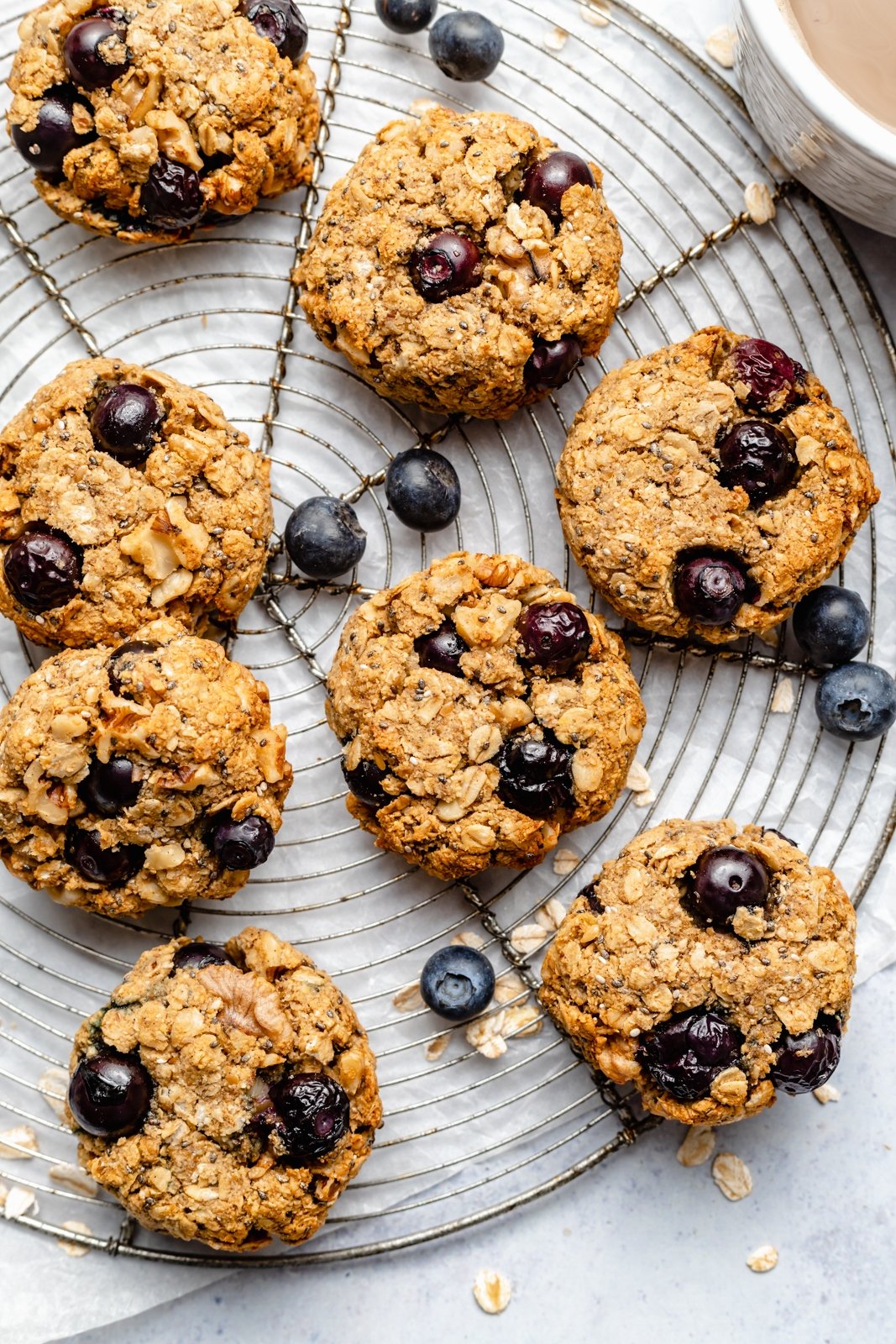 ¡Un plato de galletas de desayuno de arándanos veganas y sin gluten que saben igual que muffins de arándanos! Estas saludables galletas de desayuno de arándanos son naturalmente dulces y están llenas de nutrientes de semillas de chía, lino, avena, nueces y más ingredientes. Perfectas para congelar, ¡Es el desayuno o merienda perfecto para las semanas ocupadas! Galletas de desayuno de arándanos saludables en una rejilla de alambre