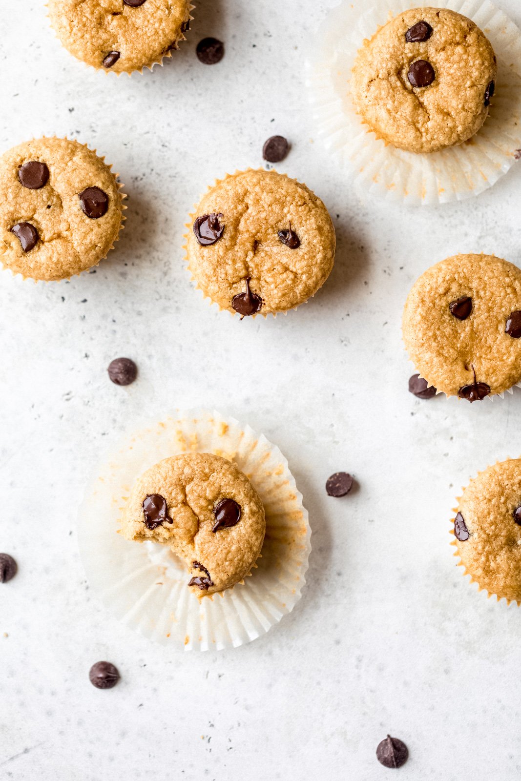 Muffins suaves de mantequilla de maní y garbanzos con deliciosas chispas de chocolate en cada bocado. Estos sencillos muffins repletos de proteínas requieren solo 7 ingredientes simples, y la masa se puede preparar directamente en una licuadora o procesador de alimentos. Fácil, apto para el congelador, sin gluten , sin lácteos, perfecto para la merienda o después del entrenamiento. Muffins de garbanzos con mantequilla de maní sin harina y chispas de chocolate en tablero gris