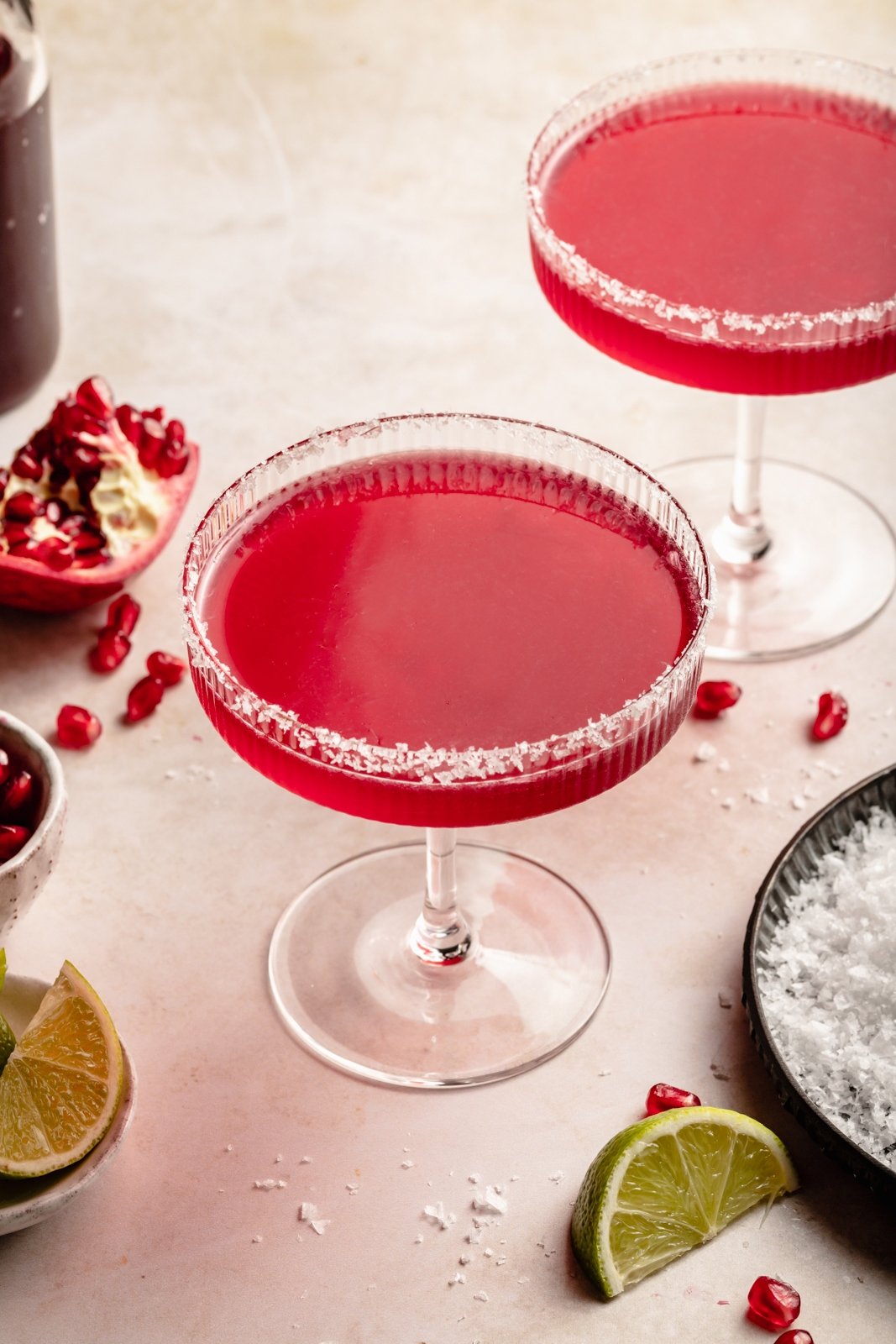 Una margarita de granada deliciosa y fácil hecha con cuatro ingredientes simples, ¡el cóctel refrescante perfecto! Use jugo de granada comprado en la tienda o hecho en casa y jarabe simple para crear un maravilloso cóctel perfecto para el entretenimiento. 2 margaritas de granada en vasos con borde de sal