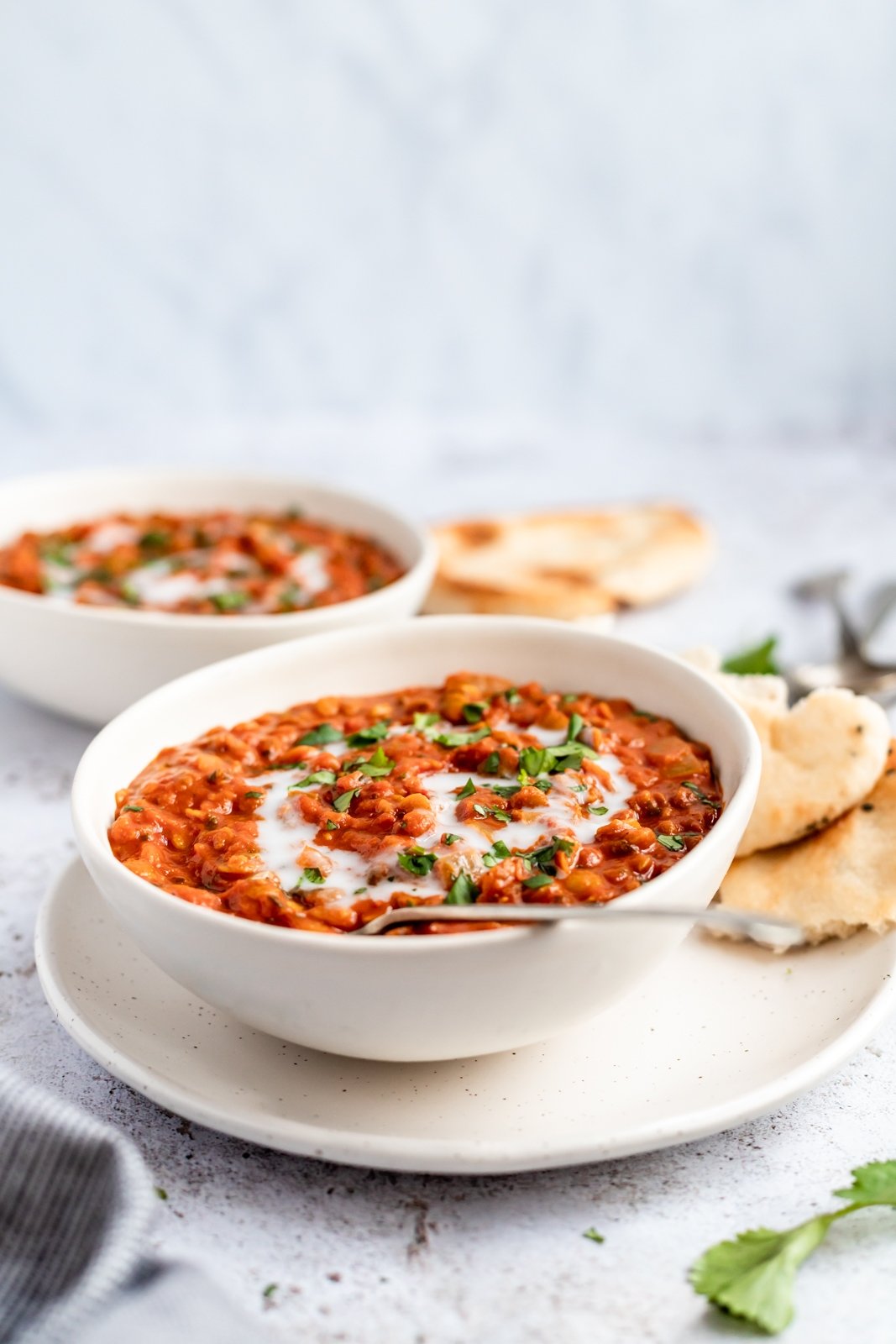 Sopa vegana nutritiva de lentejas con tomate y coco cocinada a fuego lento con deliciosas y cálidas especias como comino, cilantro y cúrcuma. ¡Esta receta cremosa de sopa de lentejas con tomate está repleta de proteínas de origen vegetal y es una preparación deliciosa para el almuerzo o la cena! Sopa vegana de coco, tomate y lentejas en un tazón