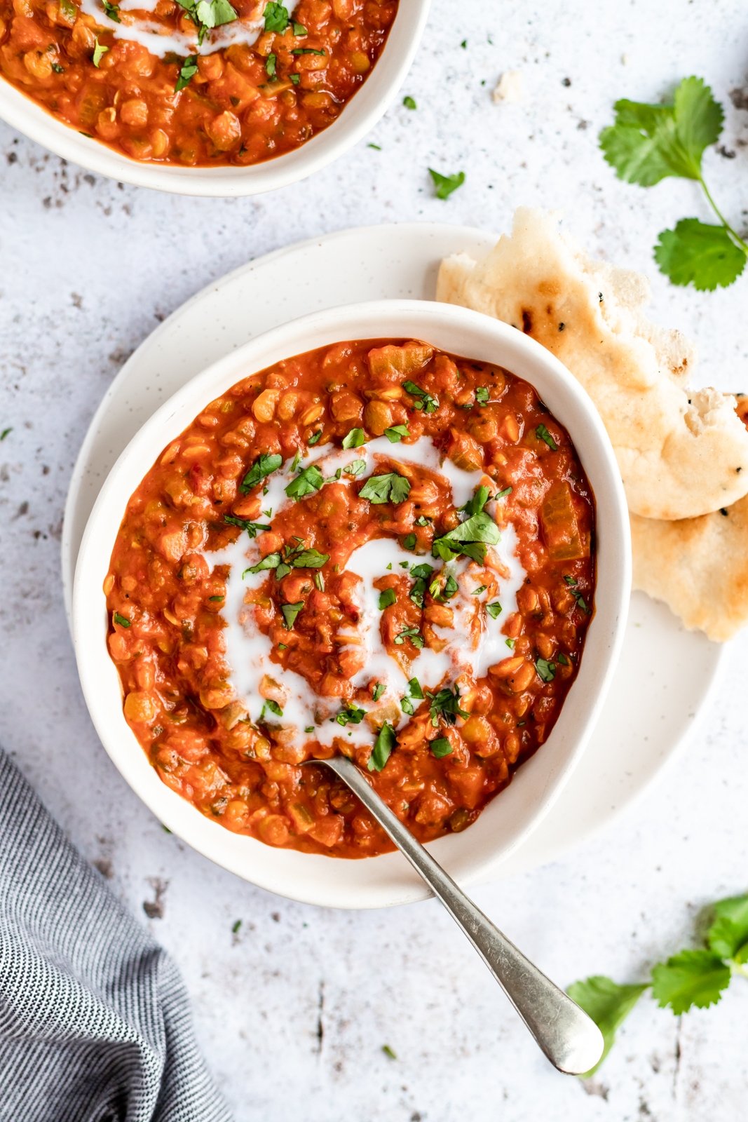 Nutritiva sopa vegana de lentejas, tomate y coco cocinada a fuego lento con deliciosas y cálidas especias como comino, cilantro y cúrcuma. ¡Esta receta de sopa cremosa de tomate y lentejas está cargada de proteínas de origen vegetal y es una deliciosa preparación para el almuerzo o la cena! Un tazón de sopa vegana de tomate y lentejas con naan