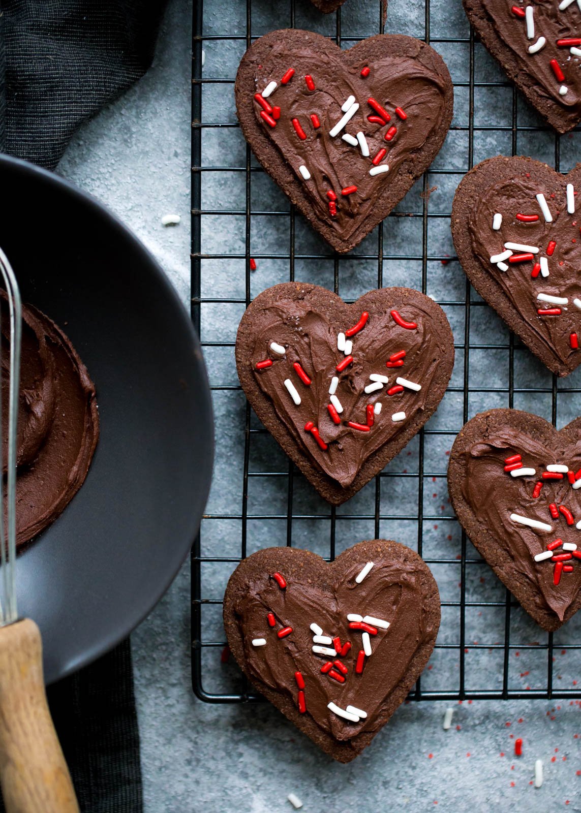Deliciosas galletas de azúcar con chocolate y harina de almendras que no contienen cereales ni gluten. ¡Esta receta fácil de galletas de un tazón se puede cortar o enrollar en masa! Cubra con glaseado de chocolate sedoso y aterciopelado si lo desea. Galletas de azúcar de chocolate con harina de almendras sin cereales cortadas en forma de corazón sobre una rejilla