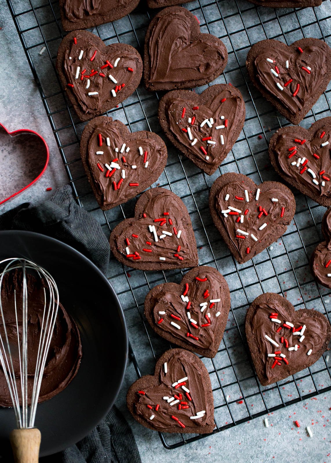 Deliciosas galletas de azúcar con chocolate y harina de almendras que no contienen cereales ni gluten. ¡Esta receta fácil de galletas de un tazón se puede cortar o enrollar en masa! Cubra con glaseado de chocolate sedoso y aterciopelado si lo desea. Galletas de azúcar de chocolate sin gluten cortadas en corazones en una rejilla de alambre