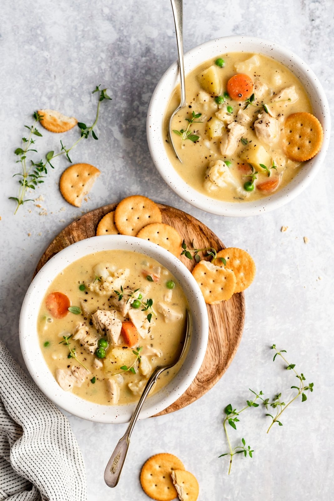 ¡Sopa de pastel de pollo saludable y reconfortante sin lácteos y deliciosa! En cambio, triture la coliflor y las papas en el caldo para obtener una consistencia rica y cremosa. Cargada de verduras, esta sopa de pastel de pollo sin gluten y paleo es la comida reconfortante ligera perfecta para los meses más fríos. Dos tazones de sopa de pastel de pollo con cuchara y galletas al costado