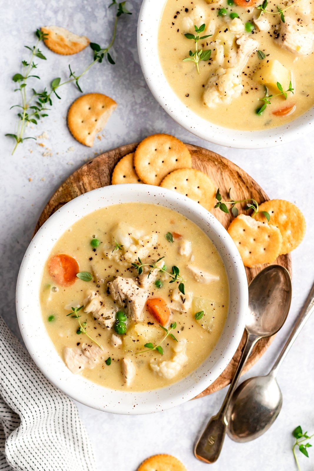 ¡Sopa de pastel de pollo saludable y reconfortante sin lácteos y deliciosa! En cambio, triture la coliflor y las papas en el caldo para obtener una consistencia rica y cremosa. Cargada de verduras, esta sopa de pastel de pollo sin gluten y paleo es la comida reconfortante ligera perfecta para los meses más fríos. Dos tazones de sopa de pastel de pollo saludable con galletas al lado