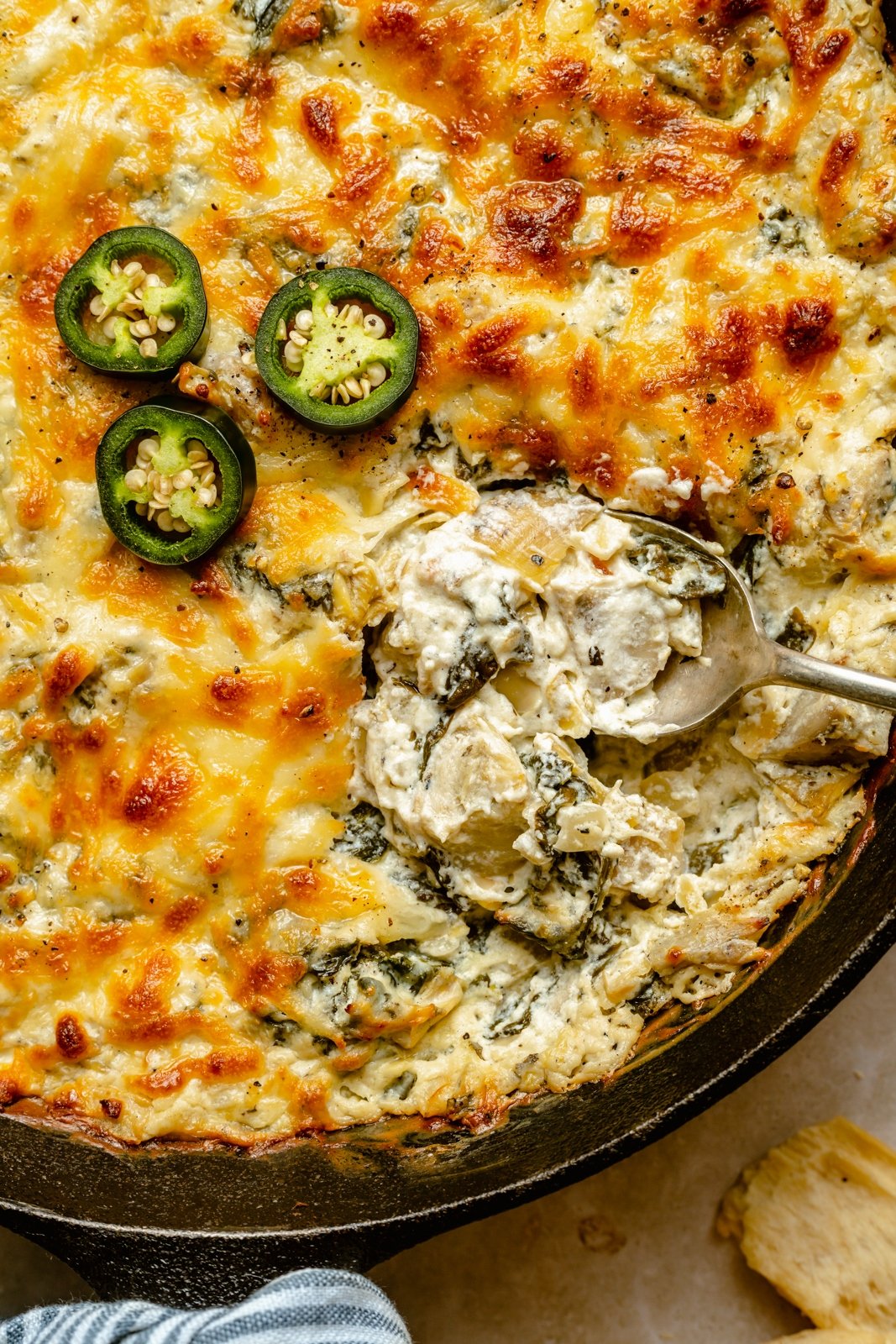 Deliciosa y cremosa salsa de alcachofas y espinacas con jalapeños, hecha con yogur griego lleno de proteínas y tres quesos. Esta sencilla, divertida y picante salsa tradicional de espinacas y alcachofas es perfecta para entretener y garantiza impresionar a amigos y familiares. ¡Sirva con nachos, verduras, galletas saladas y más! Dip picante de alcachofas y espinacas con jalapeños en una sartén