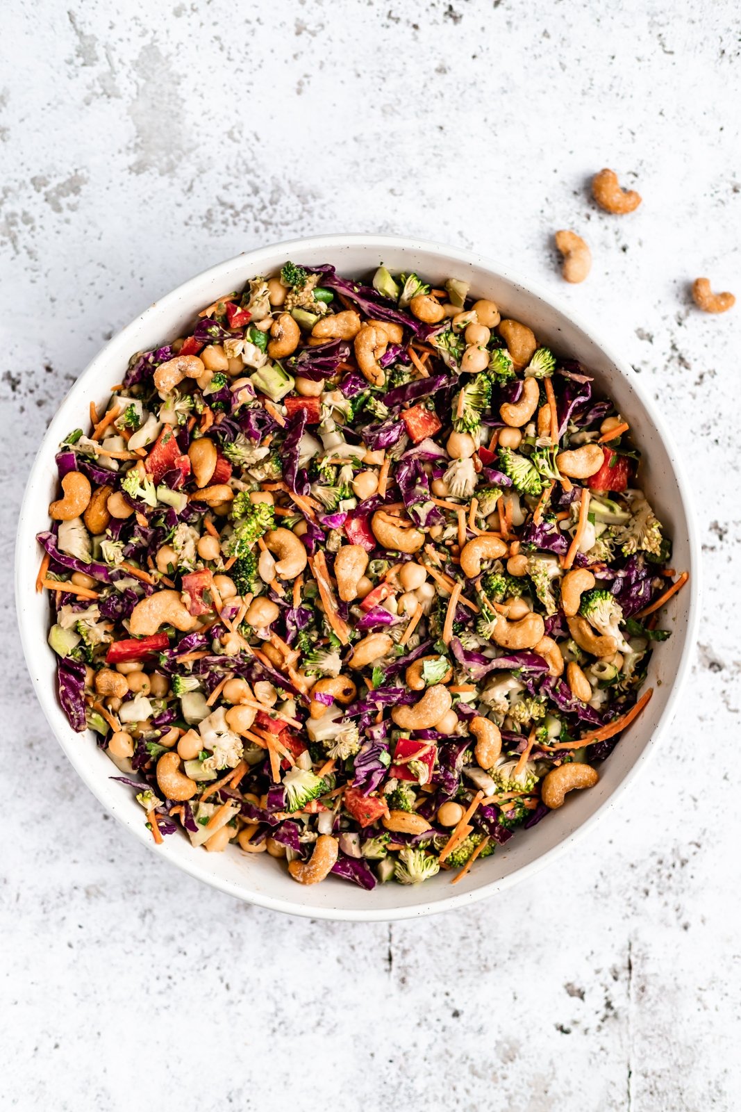 Deliciosa y saludable ensalada tailandesa de brócoli hecha con vegetales coloridos como zanahorias crujientes, repollo rojo y pimientos morrones. Mezclada con un aderezo de maní con jengibre picante, esta sencilla ensalada vegana de brócoli con anacardos está llena de deliciosas proteínas de origen vegetal gracias a los garbanzos. Ensalada vegana de brócoli tailandés picado en un tazón
