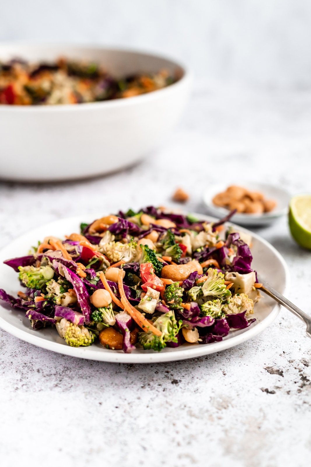 Deliciosa y saludable ensalada tailandesa de brócoli hecha con vegetales coloridos como zanahorias crujientes, repollo rojo y pimientos morrones. Mezclada con un aderezo de maní con jengibre picante, esta sencilla ensalada vegana de brócoli con anacardos está llena de deliciosas proteínas de origen vegetal gracias a los garbanzos. Ensalada de brócoli de anacardo picado en un plato