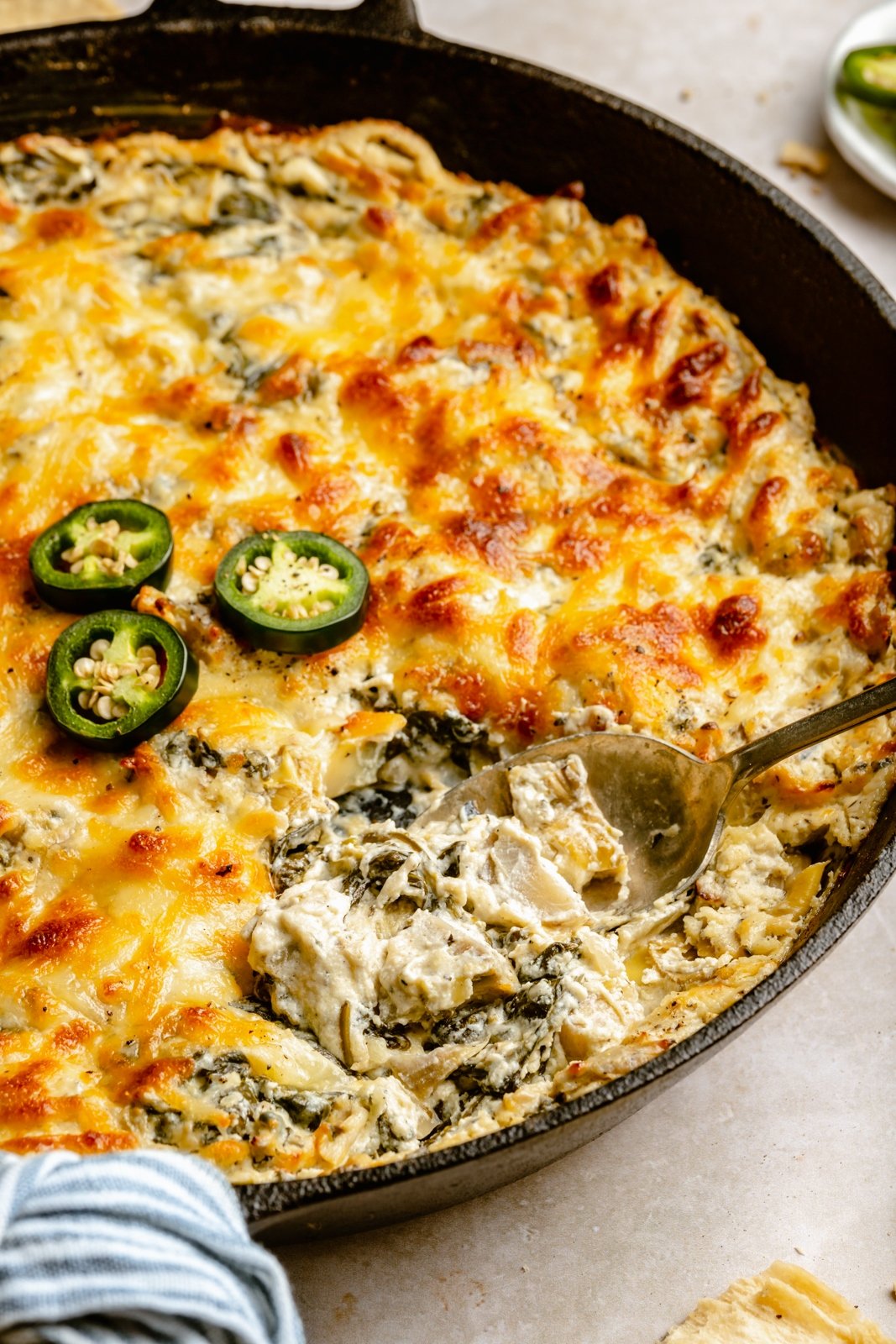 Deliciosa y cremosa salsa de alcachofas y espinacas con jalapeños, hecha con yogur griego lleno de proteínas y tres quesos. Esta sencilla, divertida y picante salsa tradicional de espinacas y alcachofas es perfecta para entretener y garantiza impresionar a amigos y familiares. ¡Sirva con nachos, verduras, galletas saladas y más! Espinacas Jalapeños Y Alcachofas Cucharadas En Una Sartén