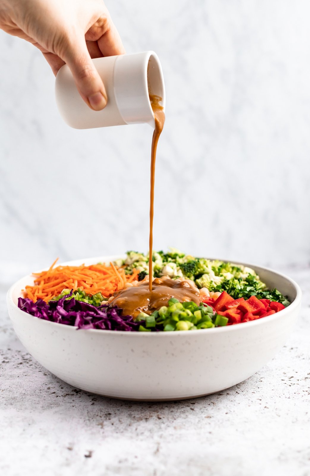 Deliciosa y saludable ensalada tailandesa de brócoli hecha con vegetales coloridos como zanahorias crujientes, repollo rojo y pimientos morrones. Mezclada con un aderezo de maní con jengibre picante, esta sencilla ensalada vegana de brócoli con anacardos está llena de deliciosas proteínas de origen vegetal gracias a los garbanzos. Vierta el aderezo picante de maní y jengibre sobre la ensalada vegana de brócoli tailandés
