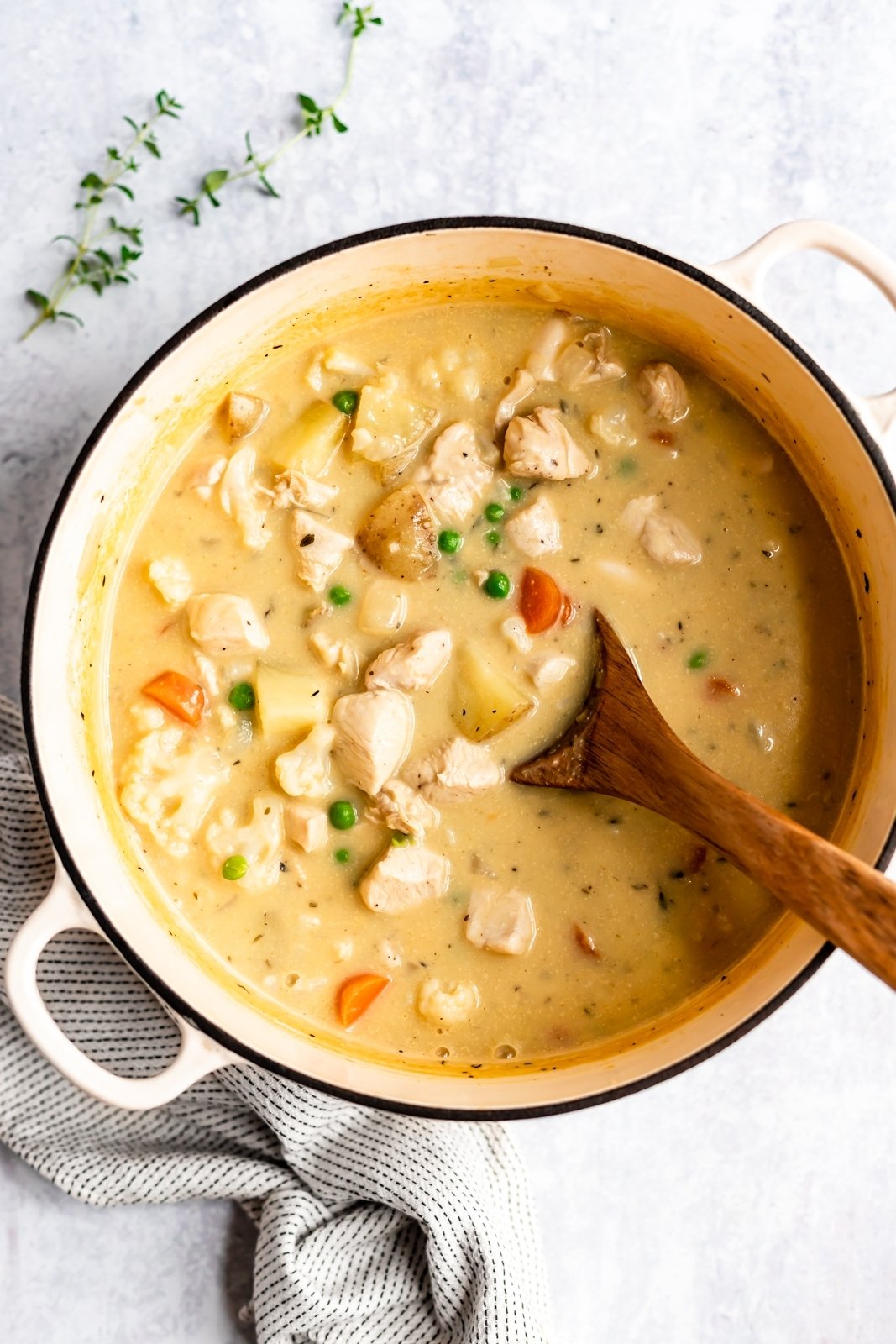 ¡Sopa de pastel de pollo cómoda y saludable sin productos lácteos y cremosa! En su lugar, la coliflor y las papas se trituran en la sopa para obtener una consistencia rica y cremosa. Esta sopa de pastel de pollo paleo sin gluten Repleta de verduras, es la comodidad ligera perfecta comida para los meses de frio! Sopa de pastel de pollo en una olla con cuchara de madera