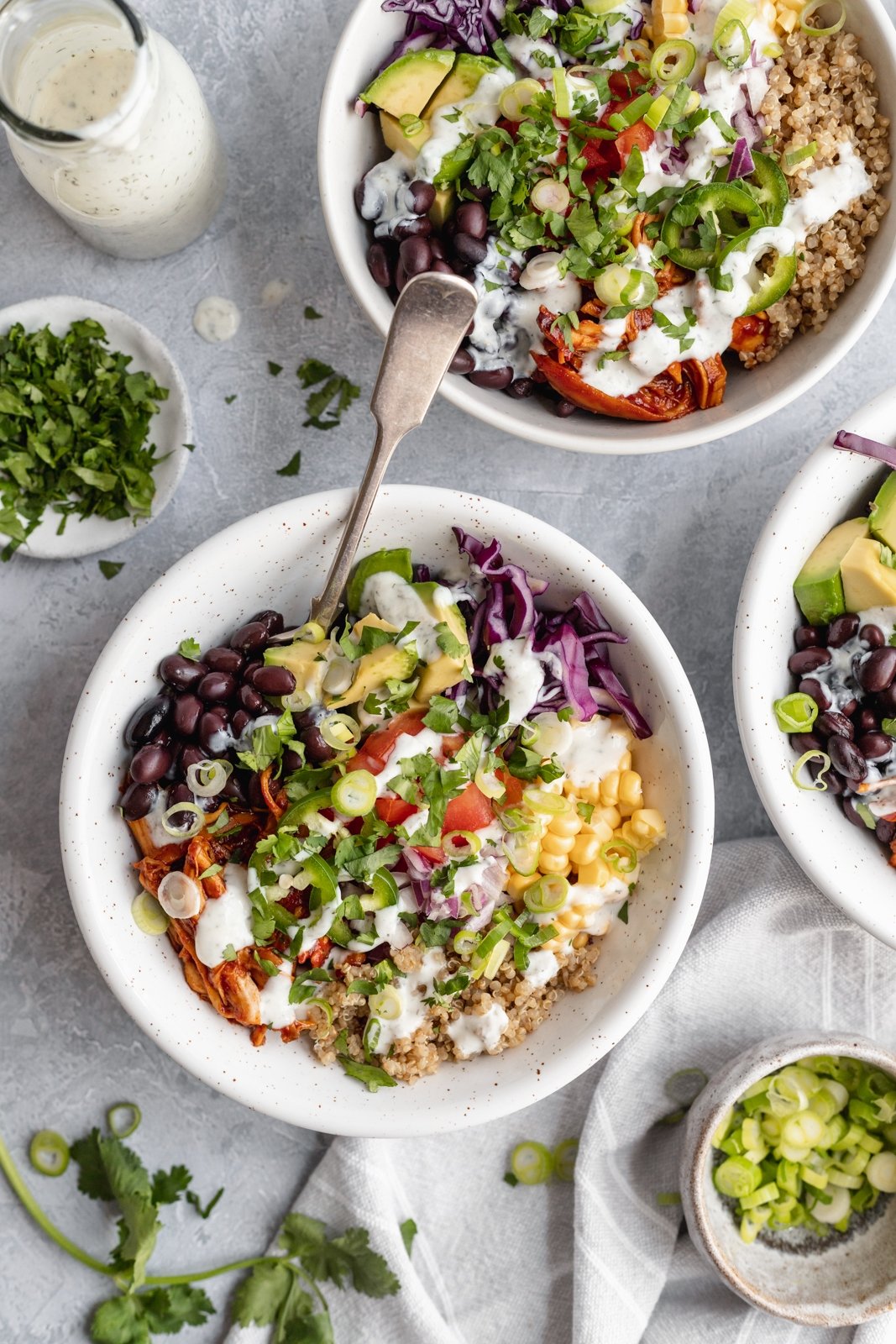 Los deliciosos tazones de quinua y pollo BBQ Ranch están rellenos con frijoles negros, repollo colorado crujiente, maíz dulce, tomates, cebollas, jalapeños, aguacate y su elección de aderezo ranch cremoso. ¡El pollo a la barbacoa en estos tazones saludables de pollo y quinua se puede preparar en la olla de cocción lenta o al horno para la cena o el almuerzo perfectos! Cuencos de quinua y pollo a la barbacoa con verduras y aderezo ranchero