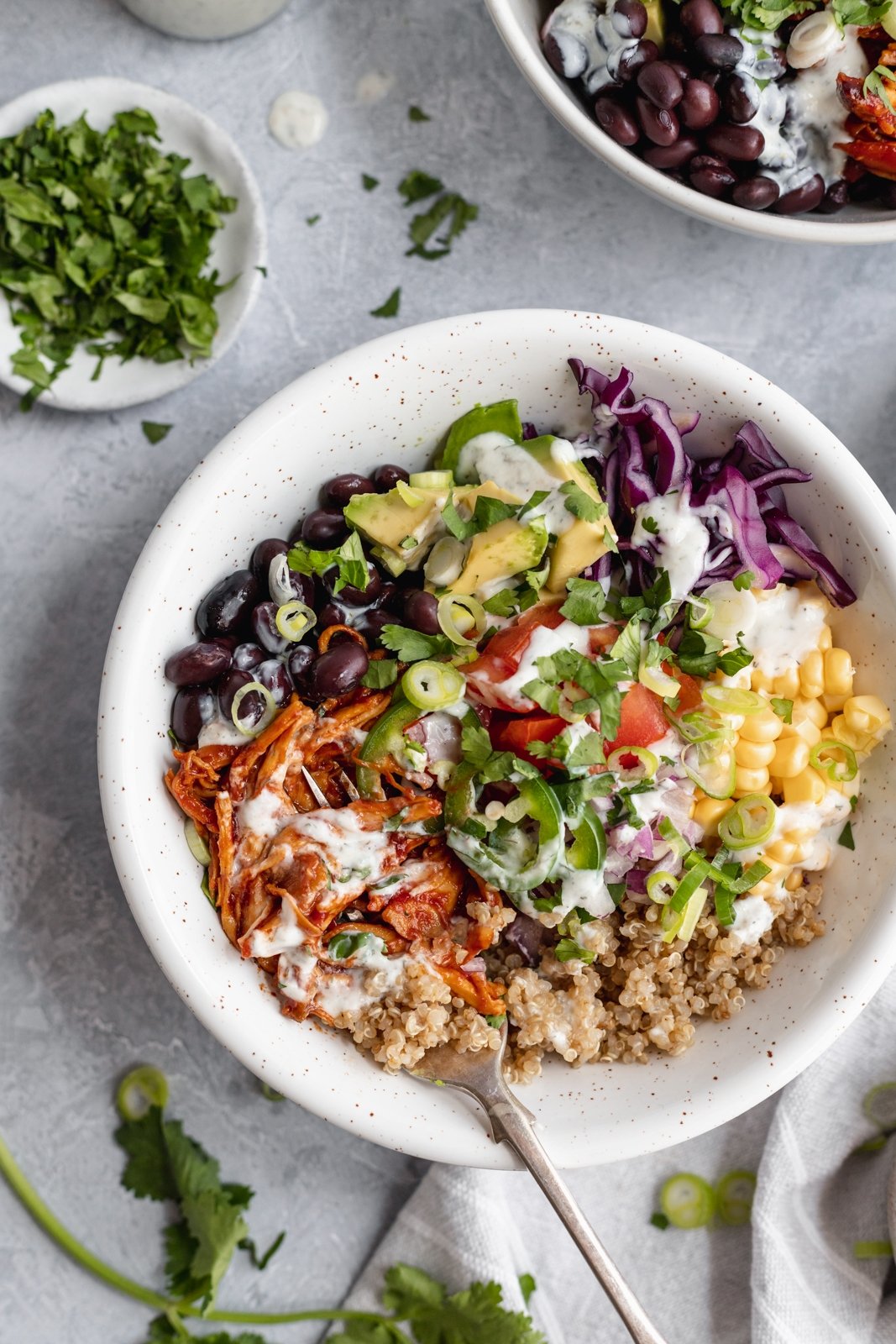 Los deliciosos tazones de quinua y pollo BBQ Ranch están rellenos con frijoles negros, repollo colorado crujiente, maíz dulce, tomates, cebollas, jalapeños, aguacate y su elección de aderezo ranch cremoso. ¡El pollo a la barbacoa en estos tazones saludables de pollo y quinua se puede preparar en la olla de cocción lenta o al horno para la cena o el almuerzo perfectos! Tazón saludable de pollo con quinoa, verduras y aderezo ranchero