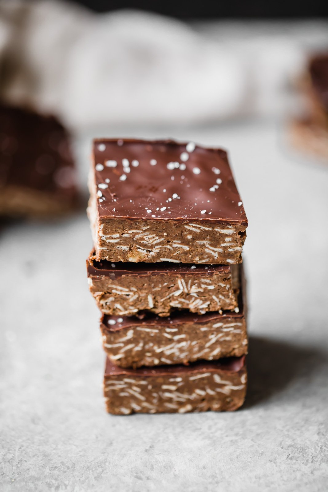 Increíbles barritas de proteína de chocolate y mantequilla de anacardo sin hornear espolvoreadas con sal marina. Estas deliciosas barritas son un delicioso refrigerio para después del entrenamiento y una delicia satisfactoria. Barras de proteína de chocolate apiladas