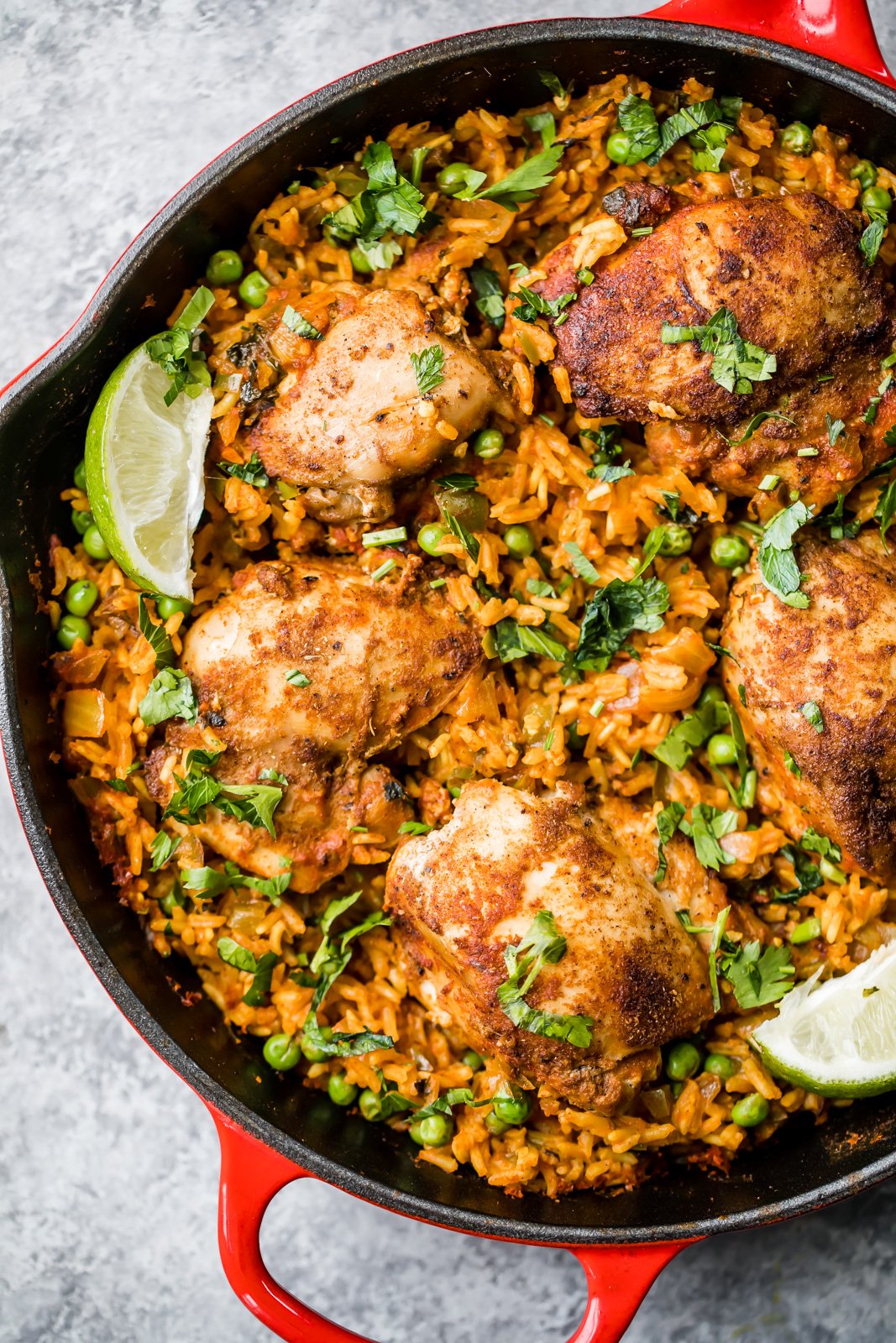 El famoso pollo y arroz puertorriqueño de mi mamá, también conocido como arroz con pollo, está hecho con sofrito de pollo sazonado con adobo casero y delicioso arroz en una sola sartén. Este plato reconfortante es fácil de preparar y es la comida nutritiva perfecta entre semana. ¡Harás esta receta una y otra vez! Arroz con pollo puertorriqueño y guisantes, adornado con cilantro y lima