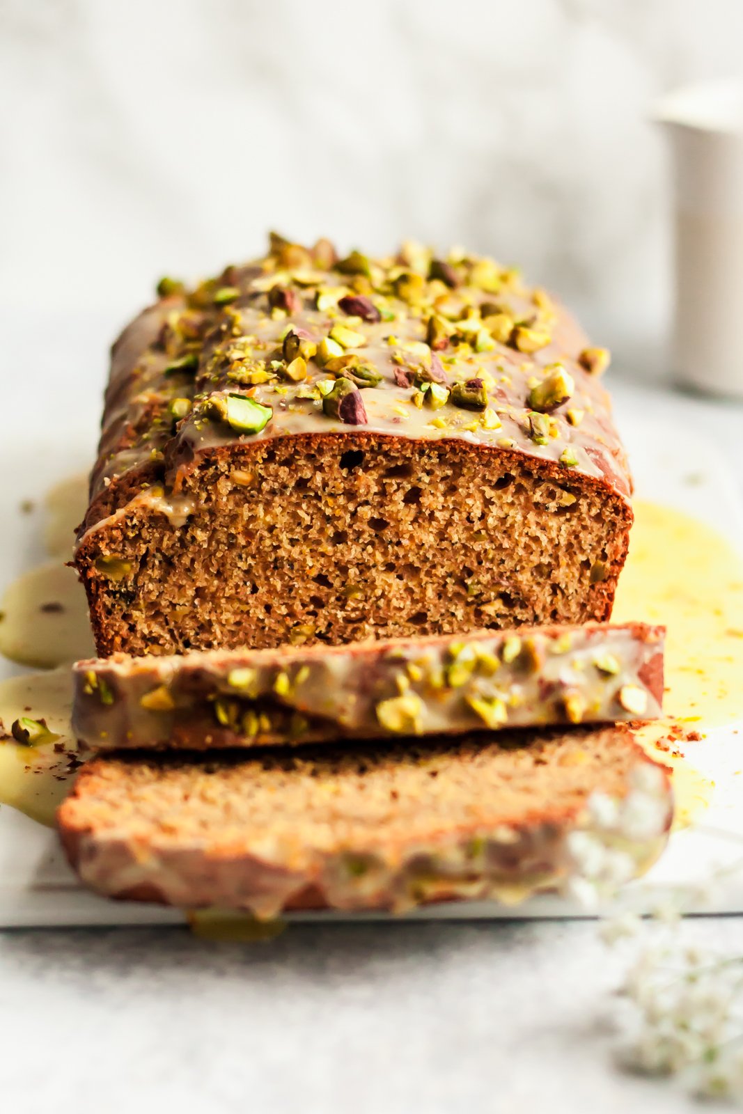 Magnífico pan de yogur de pistacho, semillas de amapola y naranja, endulzado naturalmente con miel, jugo de naranja fresco y rociado con el jugo de naranja dulce perfecto. ¡Pan de yogur delicioso y saludable para la primavera! Rodajas de pistacho en una tabla para cortar pan de naranja