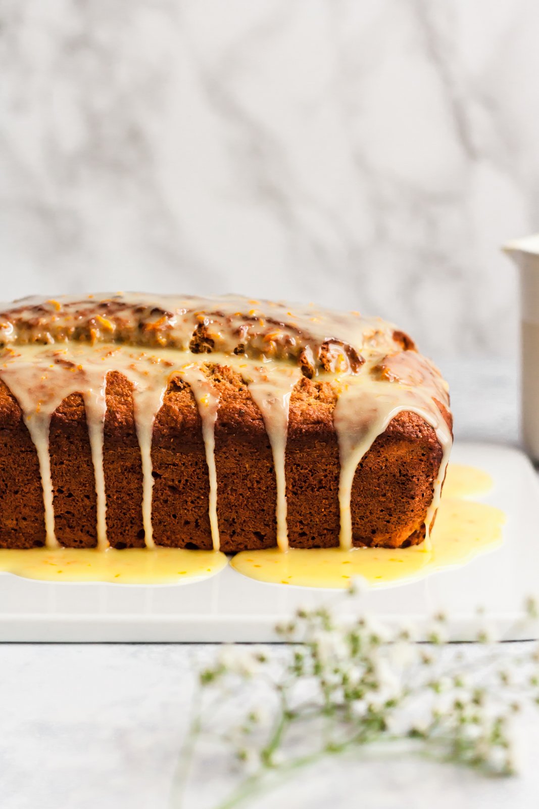 Magnífico pan de yogur con pistacho, semillas de amapola y naranja, endulzado naturalmente con miel, jugo de naranja fresco y rociado con el jugo de naranja dulce perfecto. ¡Pan de yogur delicioso y saludable para la primavera! Foto de pan de naranja en una tabla para cortar, con glaseado