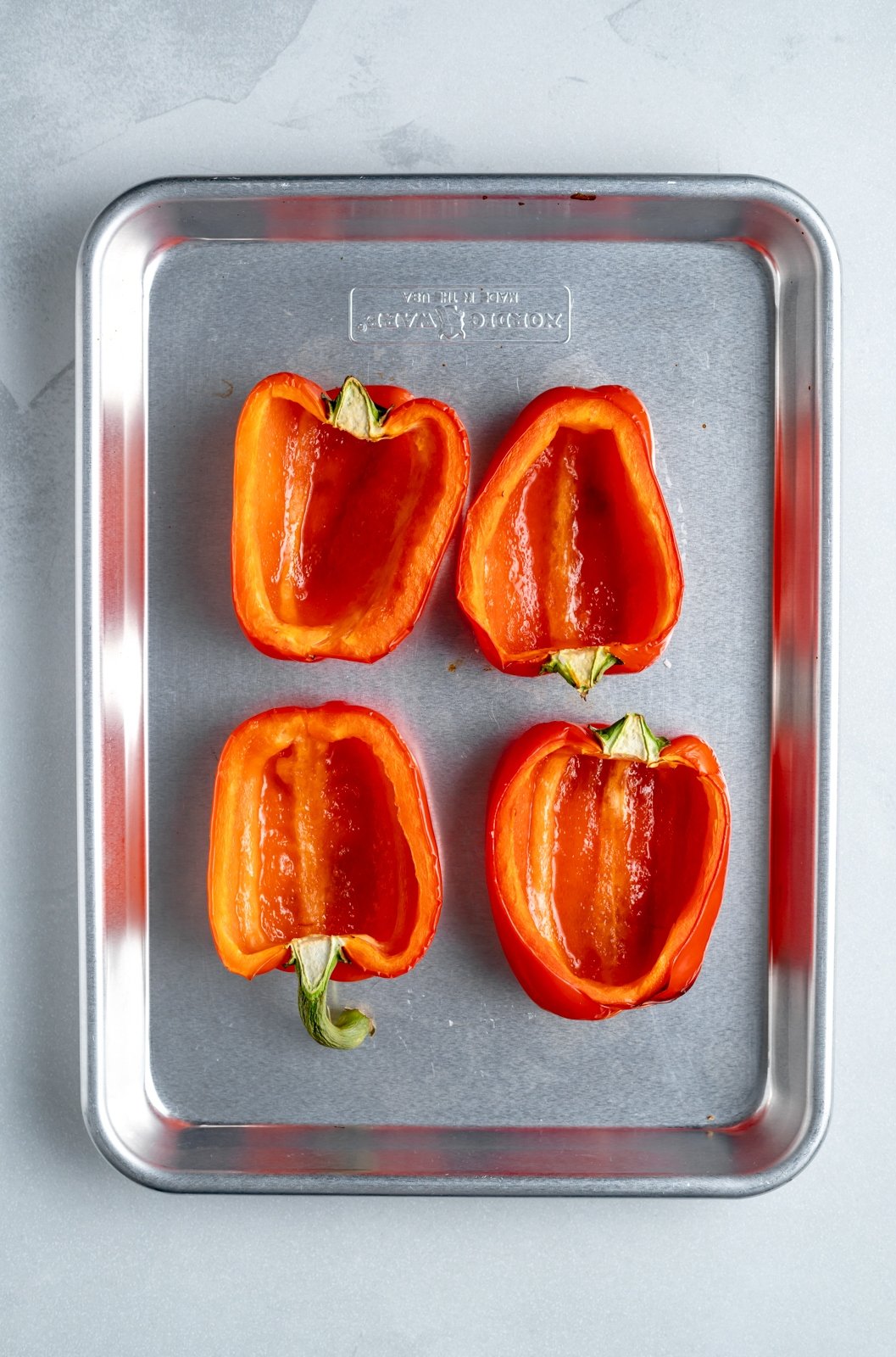 ¡Deliciosos pimientos rellenos de atún bajos en carbohidratos mezclados con verduras, yogur griego y salsa de búfalo y rociados con una capa de queso derretido! Estos sencillos pimientos rellenos de atún son el acompañamiento perfecto a la hora del almuerzo para su guarnición favorita o incluso una publicación rica en proteínas -merienda de entrenamiento. Cuatro mitades de pimiento rojo en una bandeja para hornear