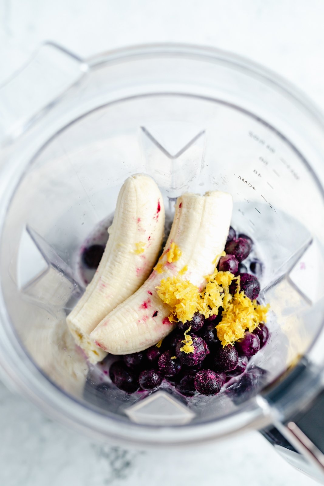 Magnífico batido de limón y arándanos hecho con jugo de limón fresco y jugosos arándanos para una explosión de sabor. Este sencillo batido vegano de limón y arándanos está endulzado naturalmente con fruta y hecho con solo cinco ingredientes simples. Opción de agregar su fortificante nutricional favorito para el perfecto desayuno o merienda! Ingredientes para batido vegano de limón y arándanos en licuadora
