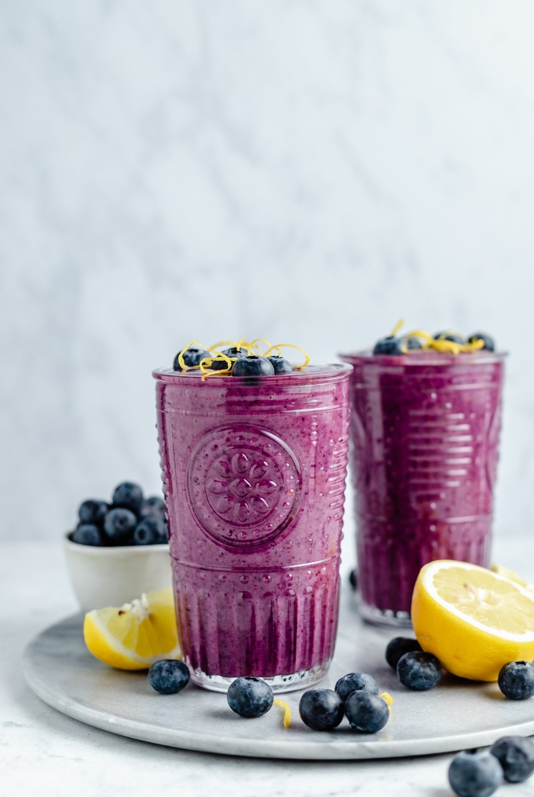 Un delicioso batido de limón y arándanos con sabores brillantes de jugo de limón fresco y jugosos arándanos. Este sencillo batido vegano de limón y arándanos se endulza de forma natural con fruta y se prepara con solo cinco ingredientes simples. ¡Opción de agregar su refuerzo nutricional favorito para el desayuno o merienda perfecto! 2 tazas de batido de limón y arándanos