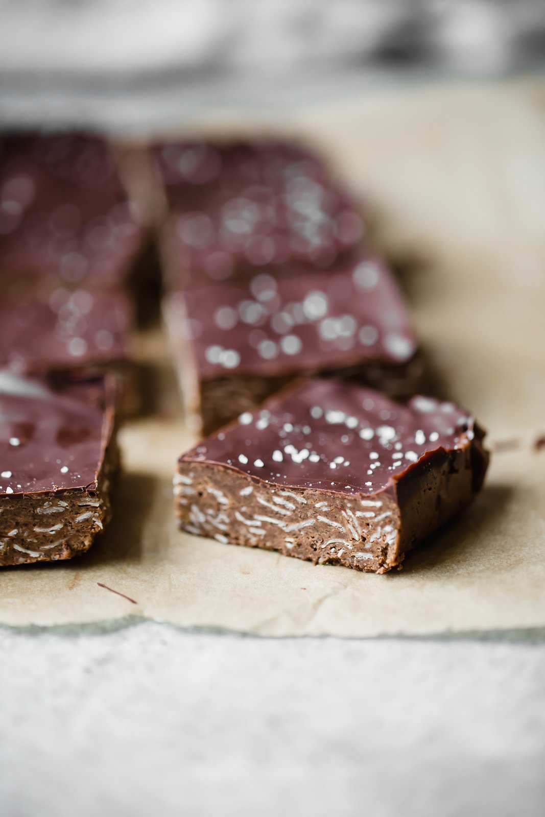 Increíbles barras de proteína de chocolate con mantequilla de anacardo sin hornear con una pizca de sal marina. Estas barras decadentes sirven deliciosos refrigerios después del entrenamiento y golosinas satisfactorias. Barras de proteína de chocolate en pergamino
