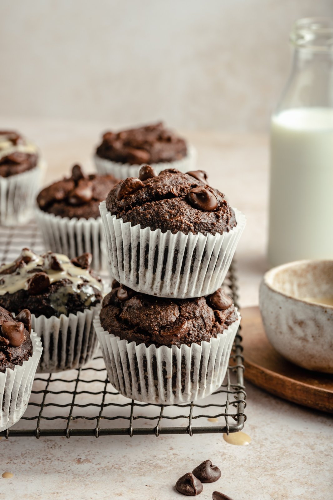 ¡Deliciosas magdalenas de banana con tahini y doble chocolate que saben a postre! Estos muffins de plátano y chocolate sin granos resultan ser paleo, sin lácteos, sin gluten y endulzados naturalmente, lo que los convierte en el desayuno o merienda perfecto. Muffins de plátano Paleo Tahini en una pila