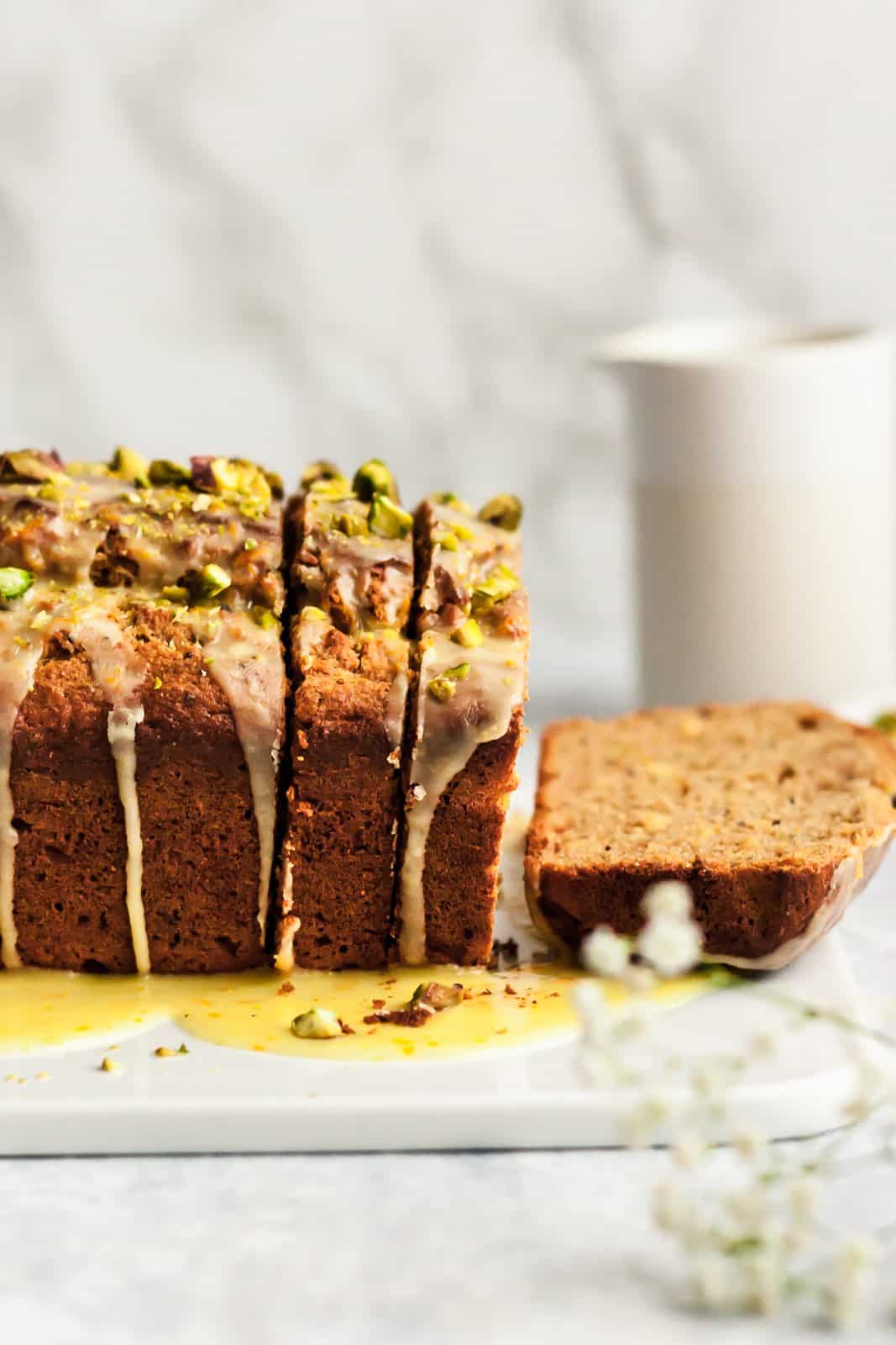 Magnífico pan de yogur con pistacho, semillas de amapola y naranja, endulzado naturalmente con miel, jugo de naranja fresco y rociado con el jugo de naranja dulce perfecto. ¡Delicioso y saludable pan de yogur para la primavera! Pan de naranja saludable en una tabla de cortar
