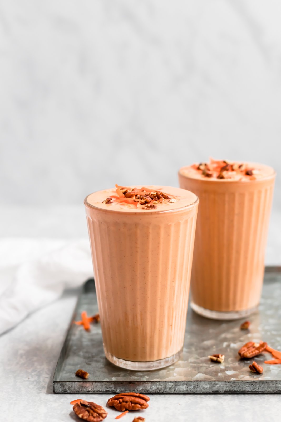 Este delicioso y saludable batido de pastel de zanahoria está hecho con ingredientes saludables como zanahorias crudas, plátanos, piña, leche de coco cremosa, yogur griego y muchas especias reconfortantes. ¡Este batido de pastel de zanahoria repleto de proteínas es el desayuno perfecto o la merienda después del entrenamiento! Dos batidos saludables de pastel de zanahoria