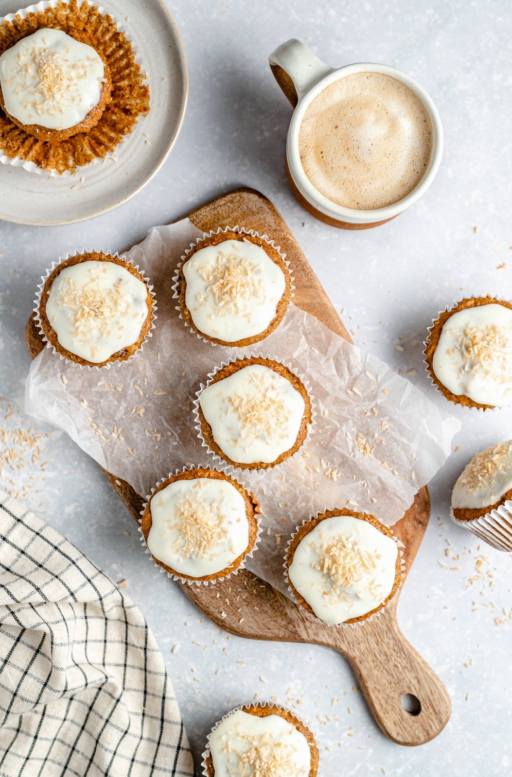 Muffins de pastel de zanahoria saludables rellenos de zanahorias, coco, pasas y nueces. Estos muffins de pastel de zanahoria deliciosamente húmedos están endulzados naturalmente con jarabe de arce puro y compota de manzana. ¡Cubra con un glaseado de queso crema ligero para un refrigerio delicioso o una golosina saludable! Muffins de pastel de zanahoria saludables con glaseado de queso crema en una tabla de madera
