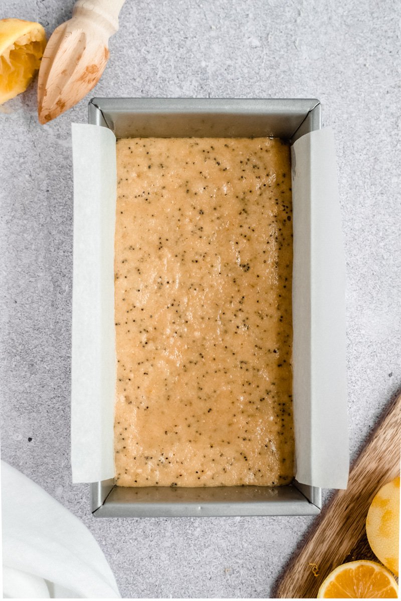 Increíble y saludable pan de semillas de amapola y limón elaborado con una mezcla de avena y harina de almendras y endulzado de forma natural con miel. Este pan de semillas de amapola y limón sin gluten está repleto de proteínas de yogur griego y se sirve en un tazón. desayuno o merienda saludable! Masa de pan con semillas de amapola y limón sin gluten en molde para pan
