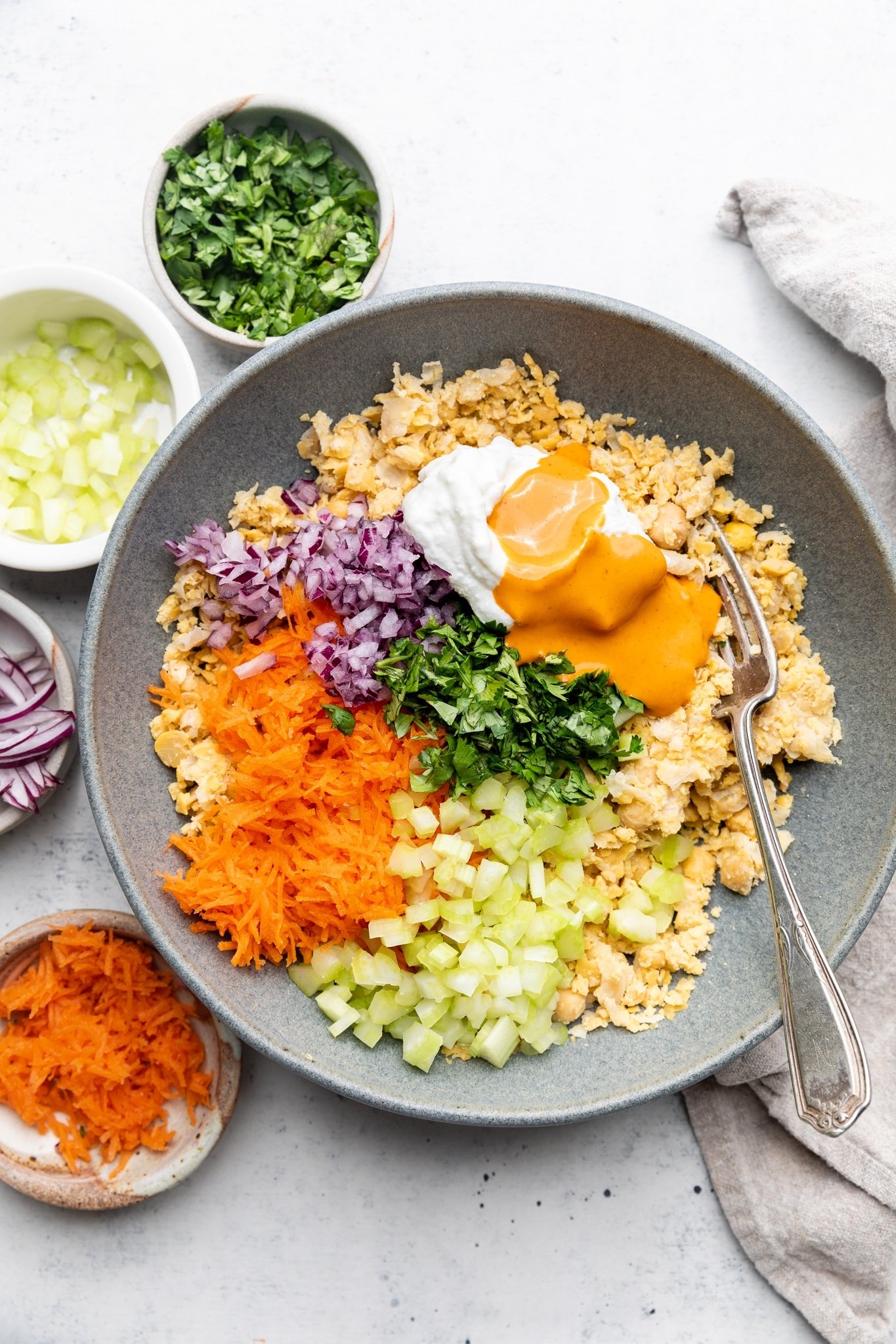 Sabrosos wraps de ensalada de garbanzos estilo buffalo con verduras crujientes, aguacate cremoso y espinacas frescas. Gracias al yogur siggi's y una lata entera de garbanzos, estos sencillos wraps de garbanzos buffalo están repletos de proteínas y son perfectos para los almuerzos empacables entre semana. Ingredientes fáciles de ensalada de garbanzos Buffalo envueltos en un tazón