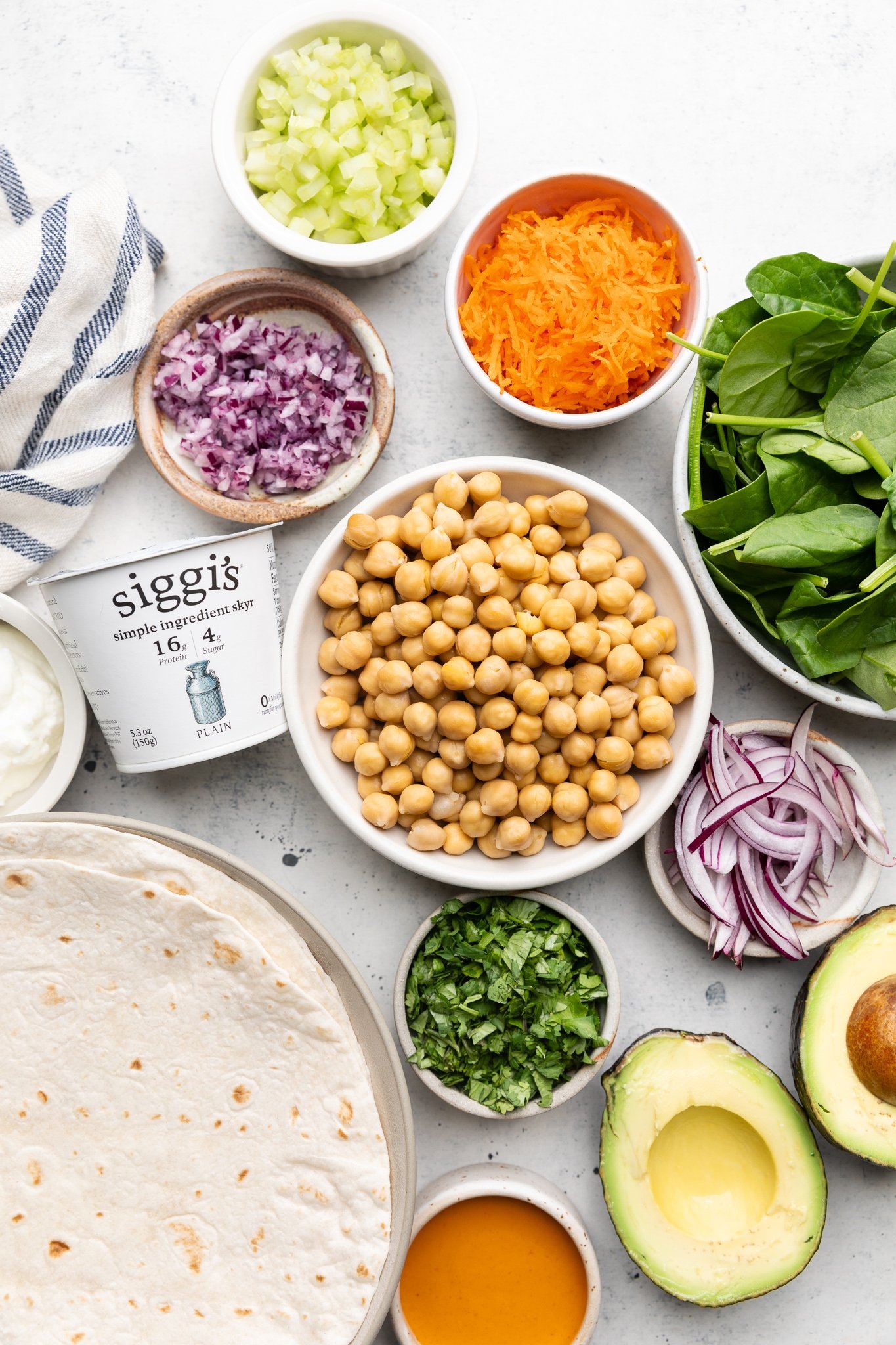 Sabrosos wraps de ensalada de garbanzos estilo buffalo con verduras crujientes, aguacate cremoso y espinacas frescas. Gracias al yogur siggi's y una lata entera de garbanzos, estos sencillos wraps de garbanzos buffalo están repletos de proteínas y son perfectos para los almuerzos empacables entre semana. Ingredientes para Ensalada Buffalo de Garbanzos en un Tazón