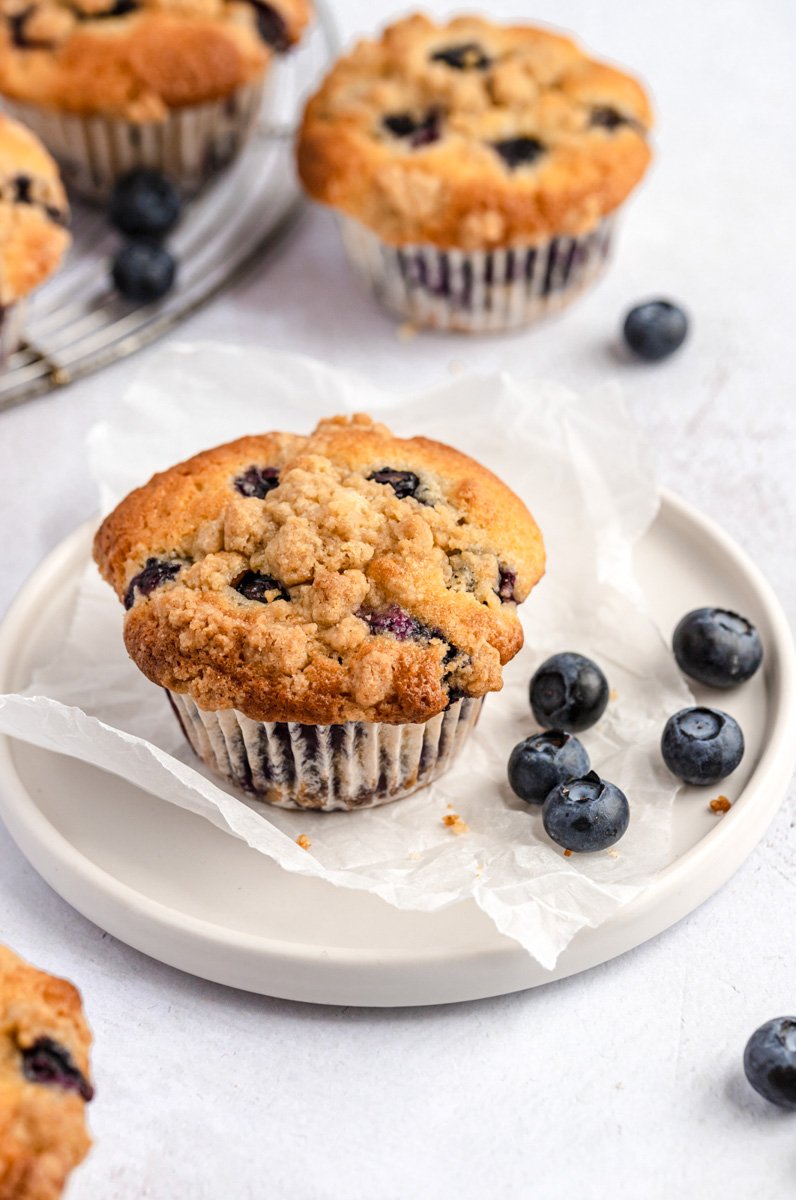 ¡Deliciosas recetas de brunch de temporada para el Día de la Madre que a tu mamá le encantarán! Ya sea que la invite a desayunar en la cama o organice un almuerzo familiar numeroso, estas recetas seguramente la harán sonreír. ¡Incluye panqueques, muffins, rollos de canela y toneladas de deliciosas recetas de brunch! Muffins de arándanos estilo panadería en un plato de arándanos
