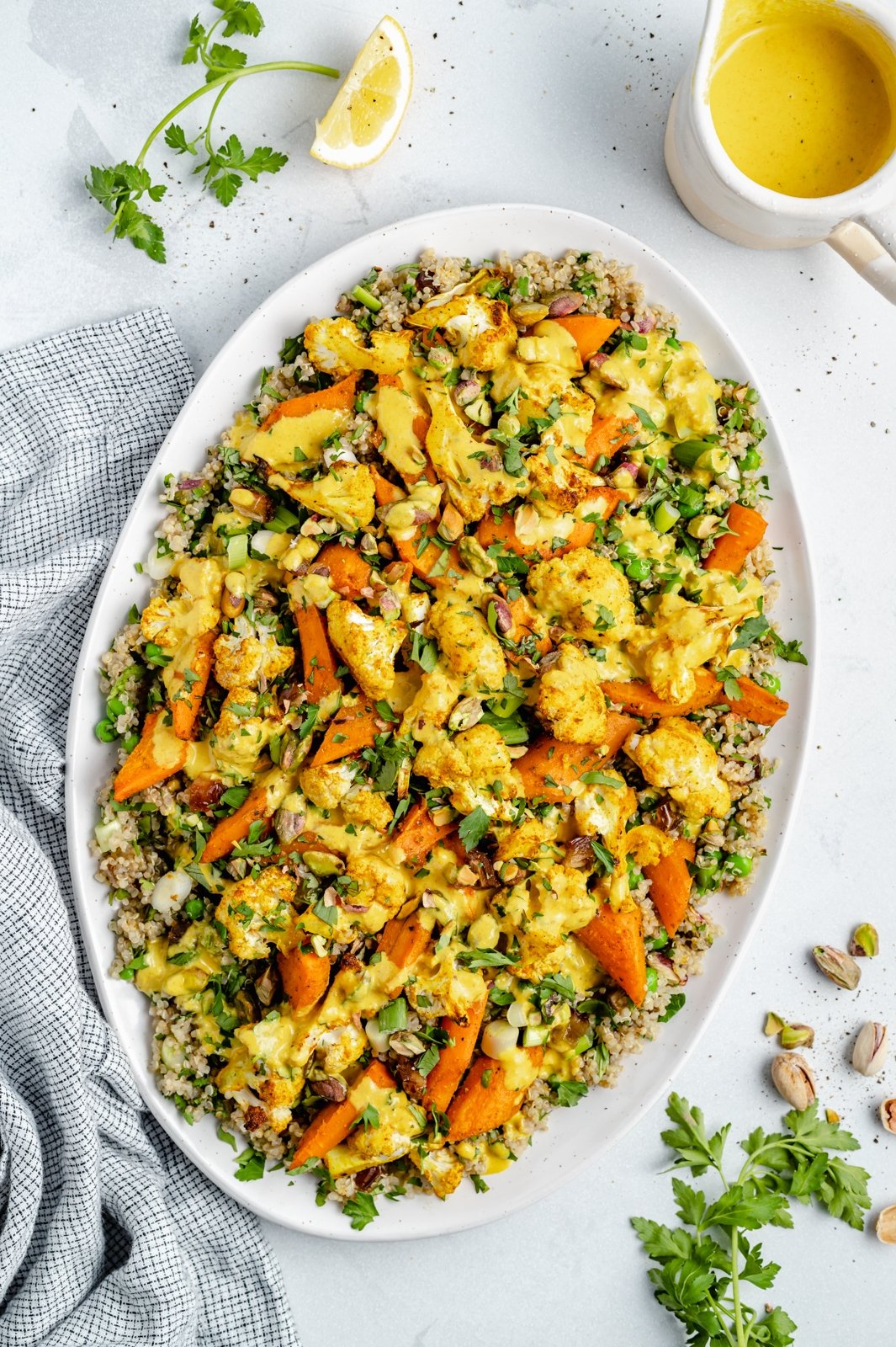 Hermosa ensalada de quinua, coliflor y zanahoria asada con hierbas frescas, dátiles dulces y pistachos salados. ¡Esta ensalada vegana de coliflor y quinua con un aderezo brillante y soleado es el almuerzo o guarnición perfecto a base de plantas! Ensalada de quinoa y zanahoria asada en un plato
