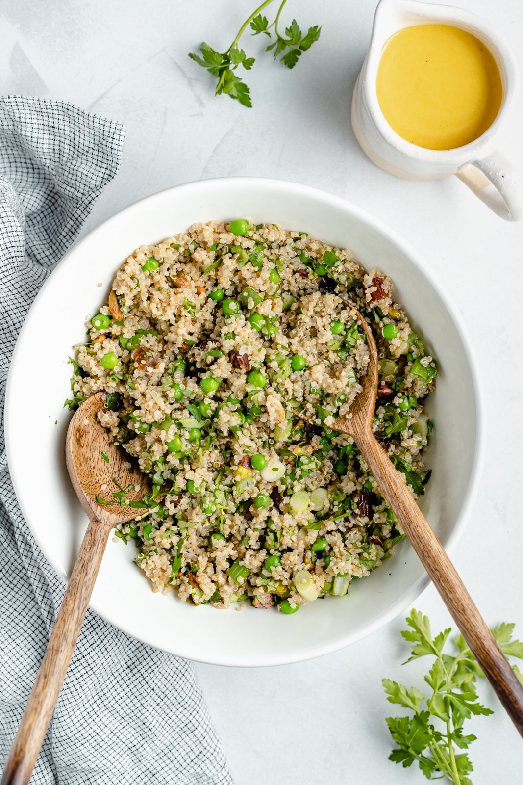 Hermosa ensalada de quinua, coliflor y zanahoria asada con hierbas frescas, deliciosos dátiles y pistachos salados. ¡Esta ensalada vegana de coliflor y quinua con aderezo soleado es el almuerzo o guarnición a base de plantas perfecta! Quinoa servida en un bol con cebollas y guisantes para una ensalada de coliflor y quinua