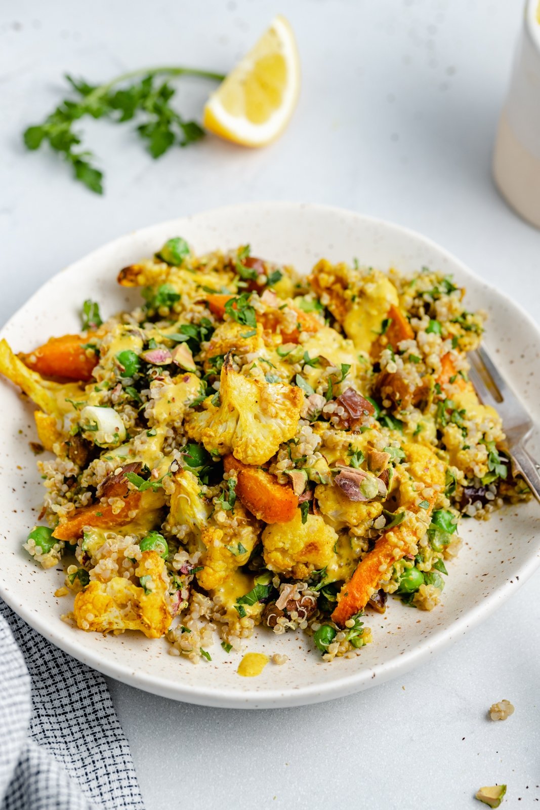 Hermosa ensalada de quinua, coliflor y zanahoria asada con hierbas frescas, dátiles dulces y pistachos salados. ¡Esta ensalada vegana de coliflor y quinua con un aderezo brillante y soleado es el almuerzo o guarnición perfecto a base de plantas! Ensalada De Coliflor Asada Con Quinoa Y Zanahorias En Un Plato