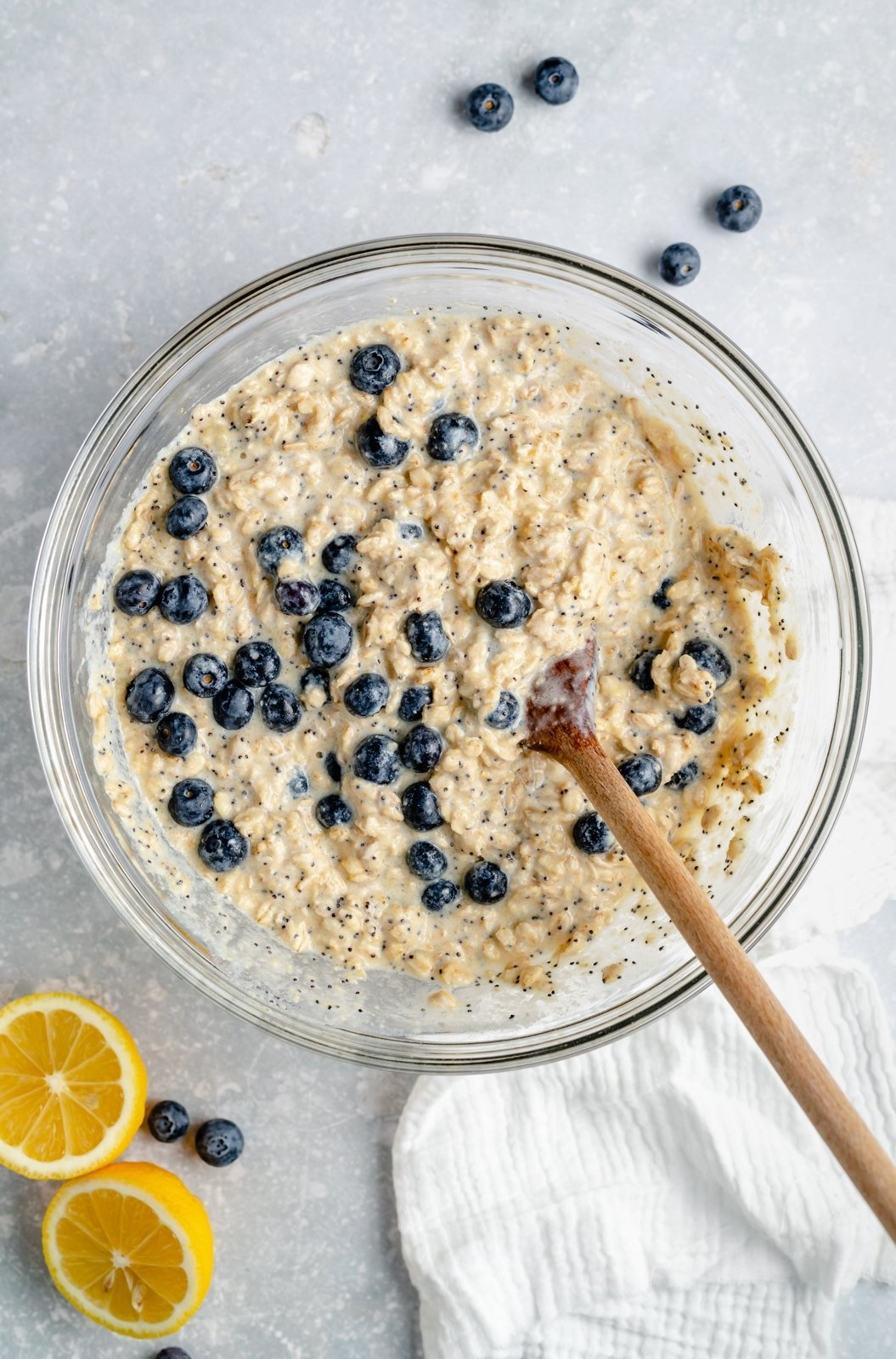 Hermosa avena horneada con limón y arándanos hecha con jugo de limón fresco y cáscara y endulzada naturalmente con jarabe de arce puro. Esta avena horneada con limón no contiene gluten ni lácteos y contiene arándanos frescos y semillas de amapola en cada bocado. Rociada con cobertura casera de yogur de limón es ¡el regalo perfecto para el desayuno! Masa de avena horneada con limón y arándanos en un tazón para mezclar