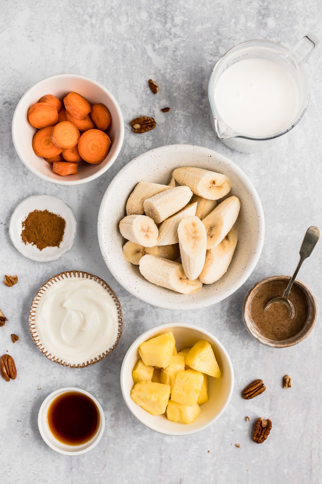 Licuado de pastel de zanahoria sabroso y saludable hecho con ingredientes saludables como zanahorias crudas, plátanos, piña, leche de coco cremosa, yogur griego y muchas especias reconfortantes. Este batido de pastel de zanahoria repleto de proteínas es perfecto para el desayuno o después del entrenamiento ¡merienda! Batido de pastel de zanahoria Ingredientes en un tazón