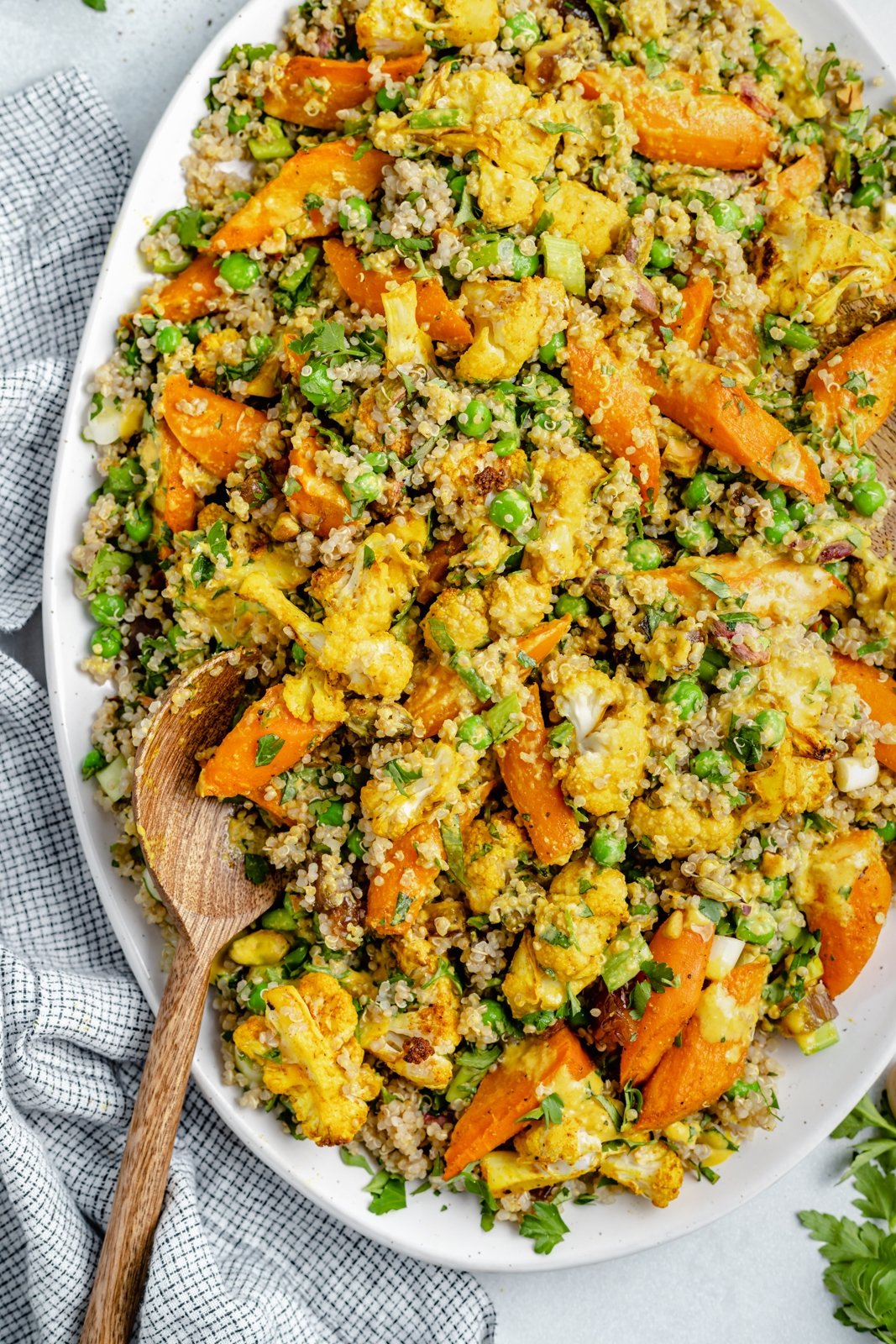 Hermosa ensalada de quinua, coliflor y zanahoria asada con hierbas frescas, dátiles dulces y pistachos salados. ¡Esta ensalada vegana de coliflor y quinua con un aderezo brillante y soleado es el almuerzo o guarnición perfecto a base de plantas! Ensalada de quinua y coliflor asada en un plato