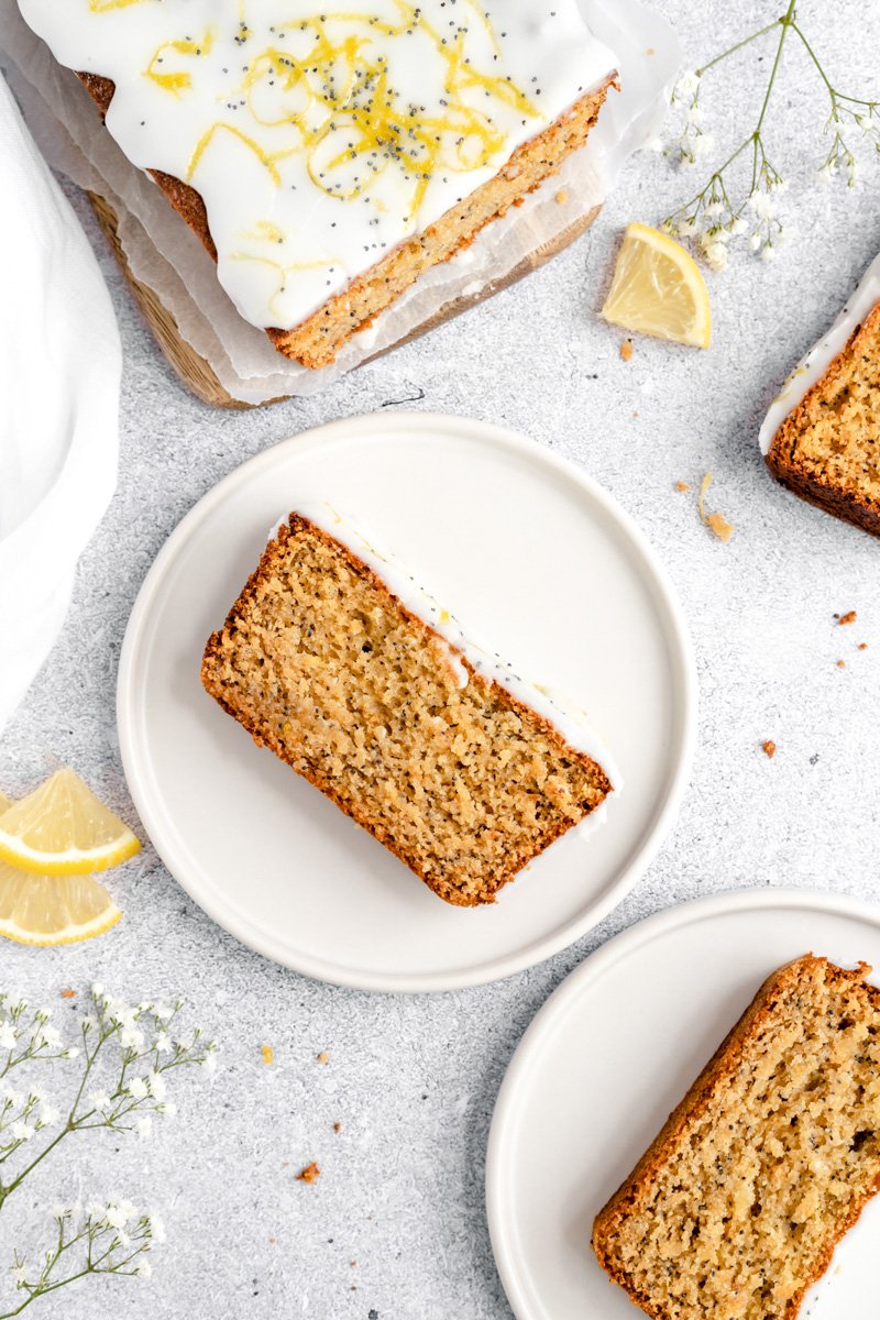 Increíble pan saludable de semillas de amapola y limón hecho de una mezcla de harina de avena y almendras y endulzado naturalmente con miel. ¡Este pan fácil de semillas de amapola y limón sin gluten está repleto de proteínas de yogur griego y es un desayuno o merienda fácil y saludable en un tazón! Una rebanada de pan de semilla de amapola de limón saludable en un plato