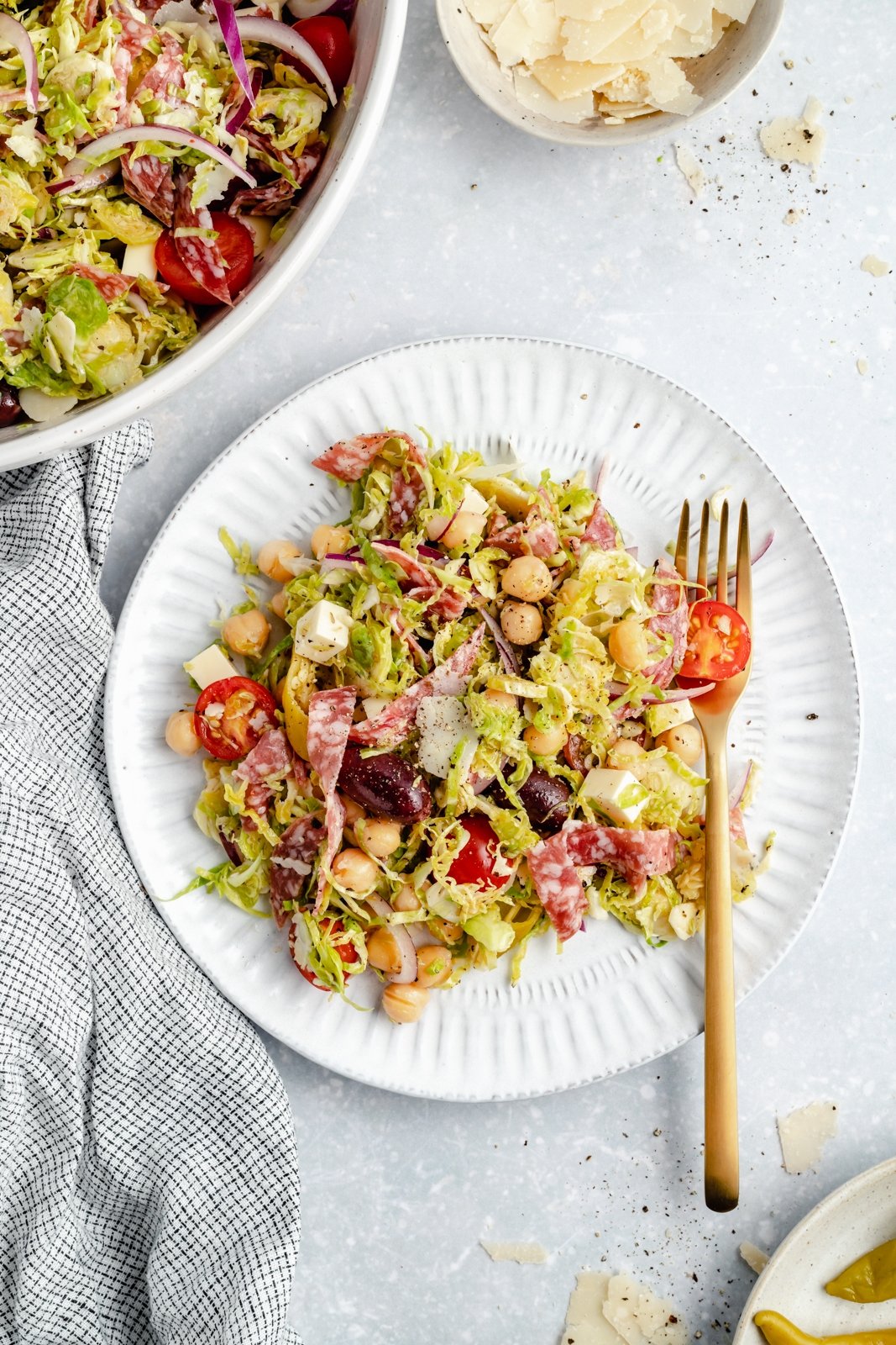 Magnífica receta de ensalada italiana picada con coles de Bruselas ralladas, garbanzos, verduras, salami, aceitunas, pepperoni y delicioso queso. ¡Esta deliciosa y fácil ensalada italiana de col rizada con col rizada picada con un ligero aderezo italiano es el almuerzo abundante perfecto o una cena fresca! Ensalada italiana saludable de coles de Bruselas picadas en un plato con un tenedor