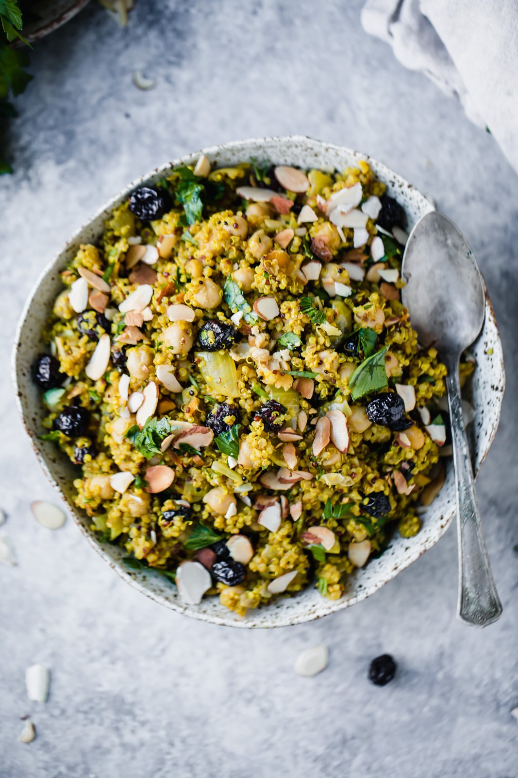¡Receta de ensalada de quinua fácil y sabrosa que es perfecta para almuerzos y cenas entre semana! Encontrarás ensalada de quinua con garbanzos, frijoles negros, pollo, mariscos y muchas verduras. Estas deliciosas quinuas están repletas de fibra y proteínas. sin gluten será tu nueva forma favorita de cocinar con quinua. Ensalada marroquí de garbanzos y quinoa con una cuchara en un bol