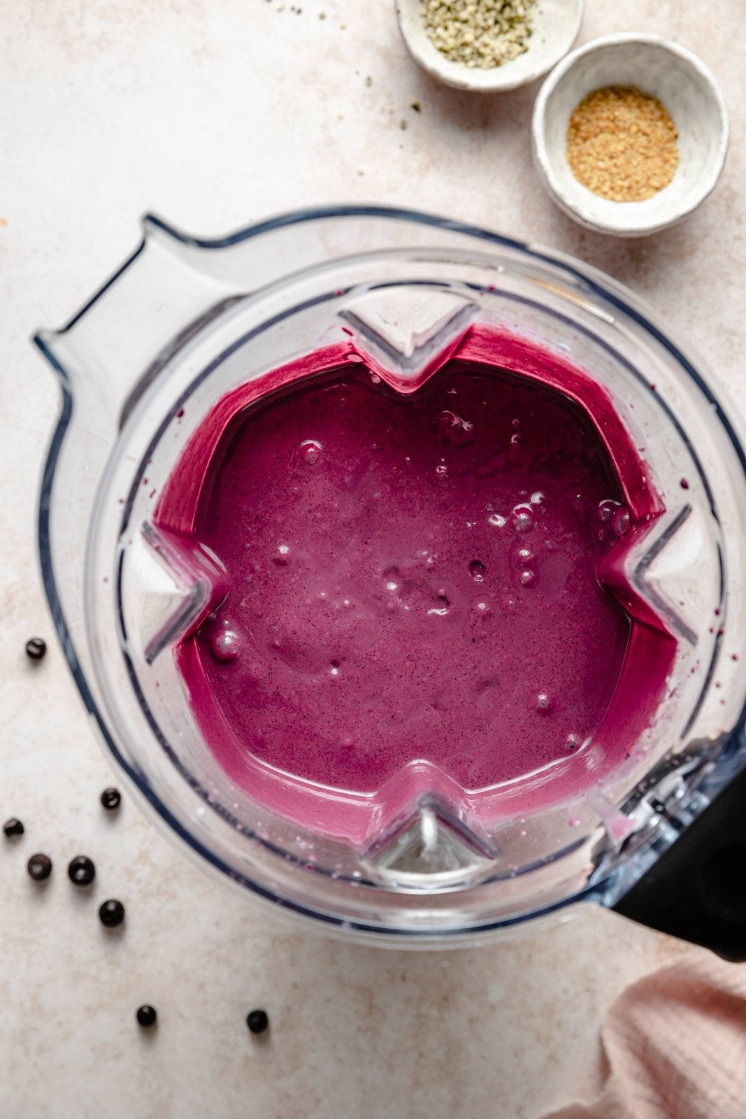 ¡Increíble batido de arándanos hecho con arándanos silvestres que sabe igual que muffins de arándanos recién horneados! Este nutritivo batido de arándanos y muffins no contiene plátano, es naturalmente dulce y está lleno de proteína griega en el yogur y lleno de sabor a muffins y lino gracias a la avena. Este delicioso desayuno o merienda incluye complementos de sabor opcionales! Vista de arriba hacia abajo del batido de arándanos silvestres en la licuadora