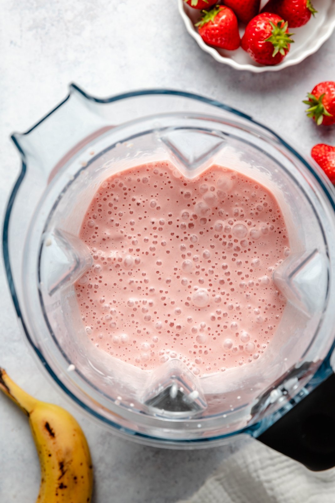 El batido de plátano, fresa y mantequilla de maní más cremoso que te deja desnudo y delicioso. ¡Solo necesitas 5 minutos y 4 ingredientes simples para hacer este increíble batido con un sabor nostálgico de plátano, mantequilla de maní y mermelada! Este batido de mantequilla de maní, plátano y fresa es vegano y está repleto de grasas saludables y proteínas, lo que lo convierte en el desayuno o merienda perfecto. Vista superior del batido de fresa, plátano y mantequilla de maní en la licuadora