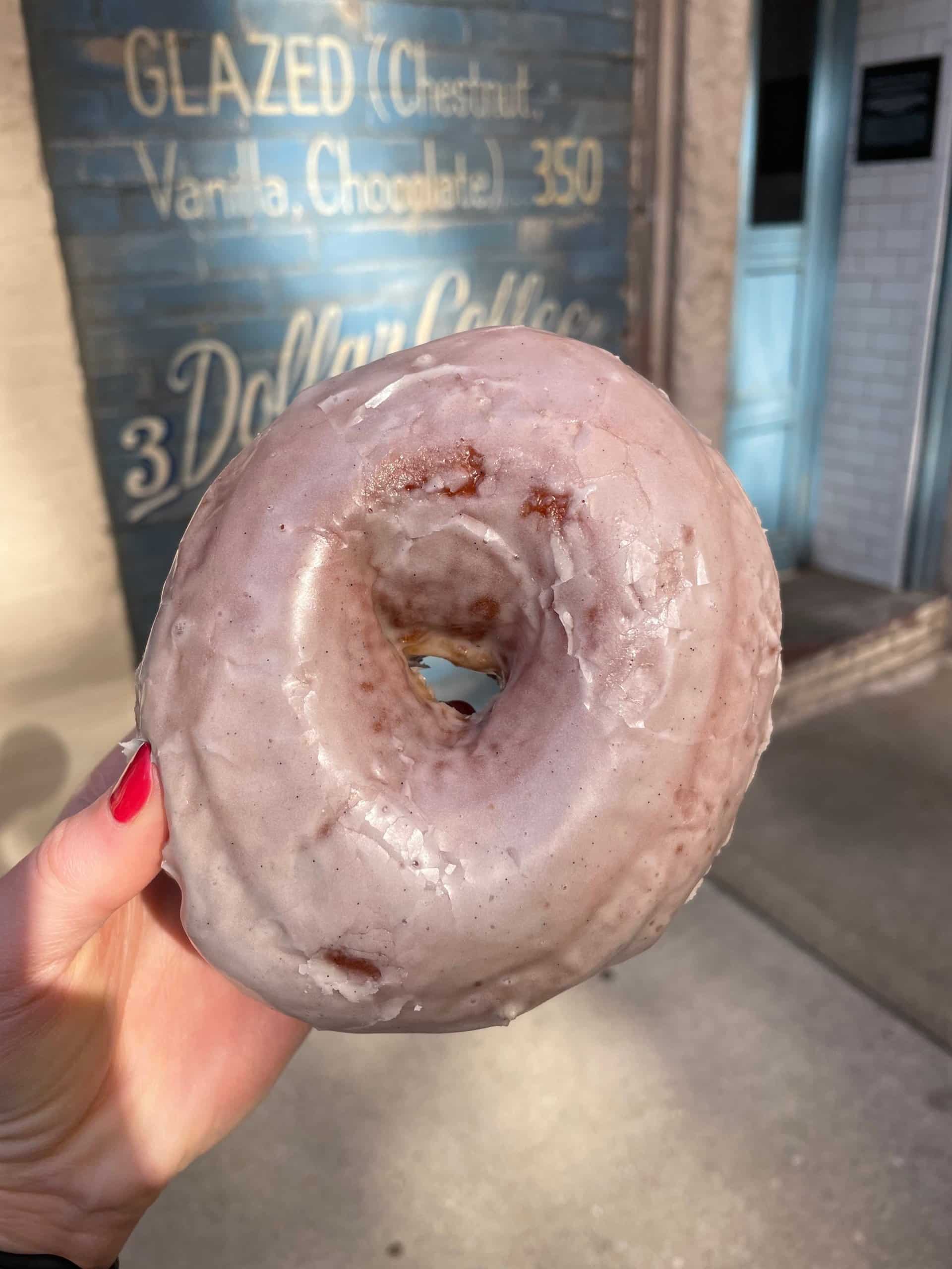 ¡Es hora de hacer frente a tu gusto por lo dulce con las mejores donas de Chicago! Para la próxima guía de la serie Ambitious Chicago Kitchen, encuestamos a nuestra audiencia y exploramos la ciudad para encontrar las mejores donas y tiendas de donas. Encontrará sabores deliciosos y únicos que son el regalo perfecto para sorprender a los invitados de fuera de la ciudad. sosteniendo una dona de chicago al lado del letrero